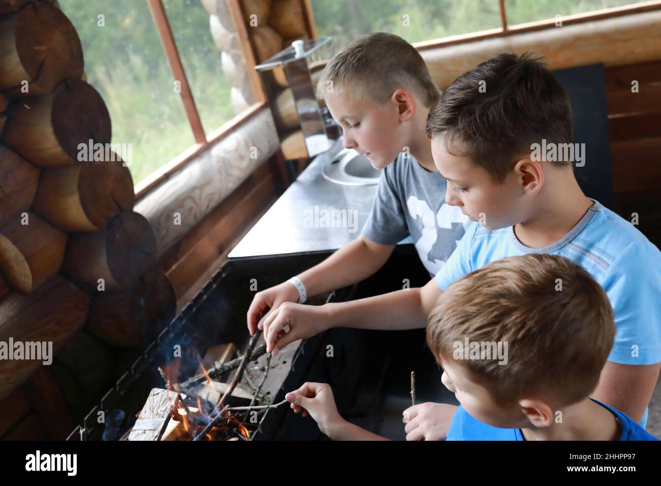 Drei Kinder zünden Feuerholz im Grill, Karelia Stockfoto