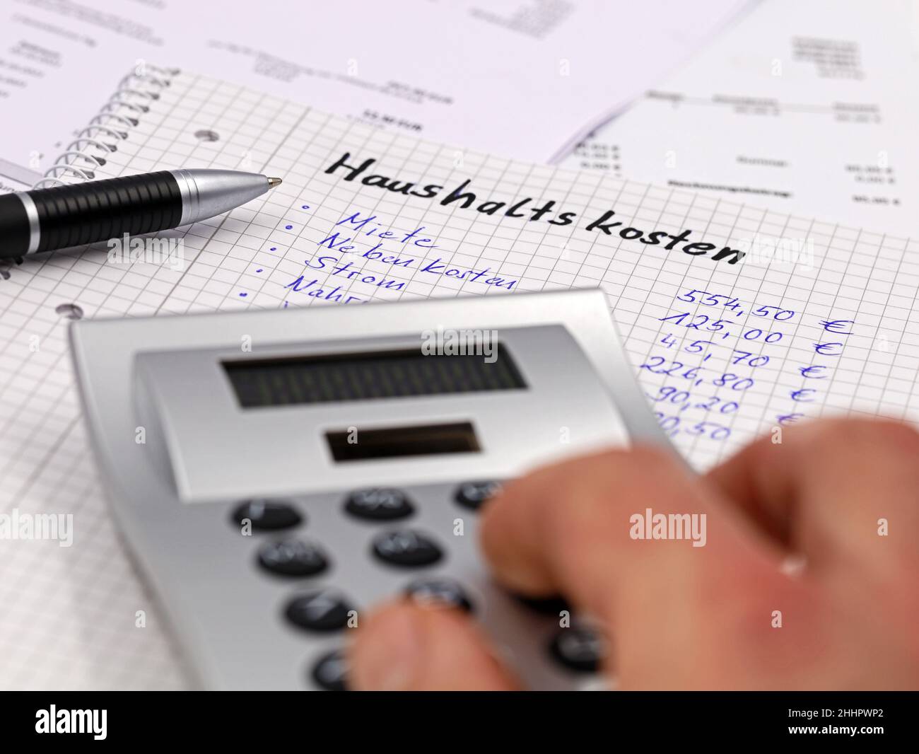 Berechnung der monatlichen Haushaltsausgaben mit einem Rechner in deutscher Sprache Stockfoto