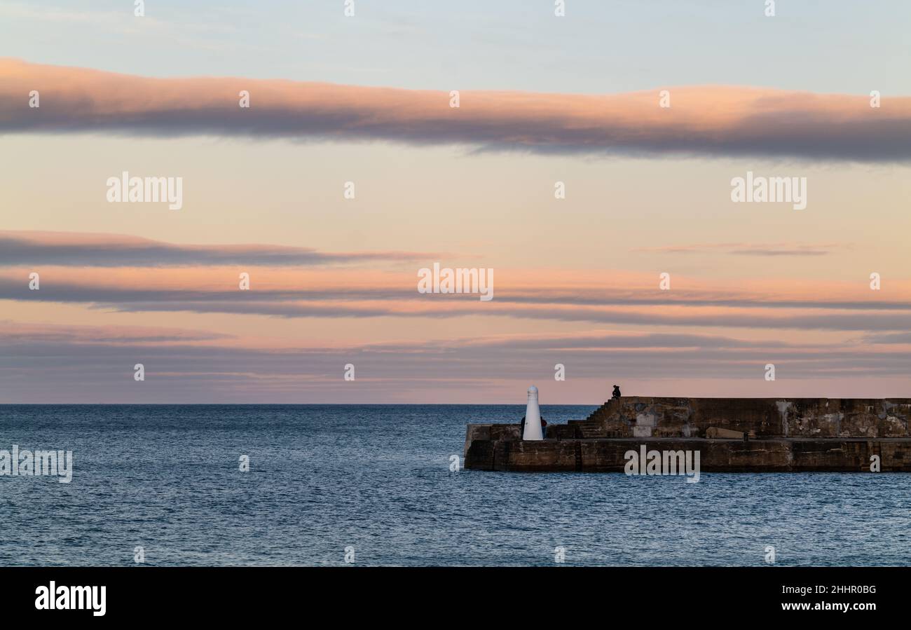 CULLEN, MORAY, SCHOTTLAND - 23. JANUAR 2022: Dies sind die Wolkenlinien, die am Sonntag, dem 23. Januar, in Cullen, Moray, Schottland die letzten Sonnenstrahlen bekommen Stockfoto