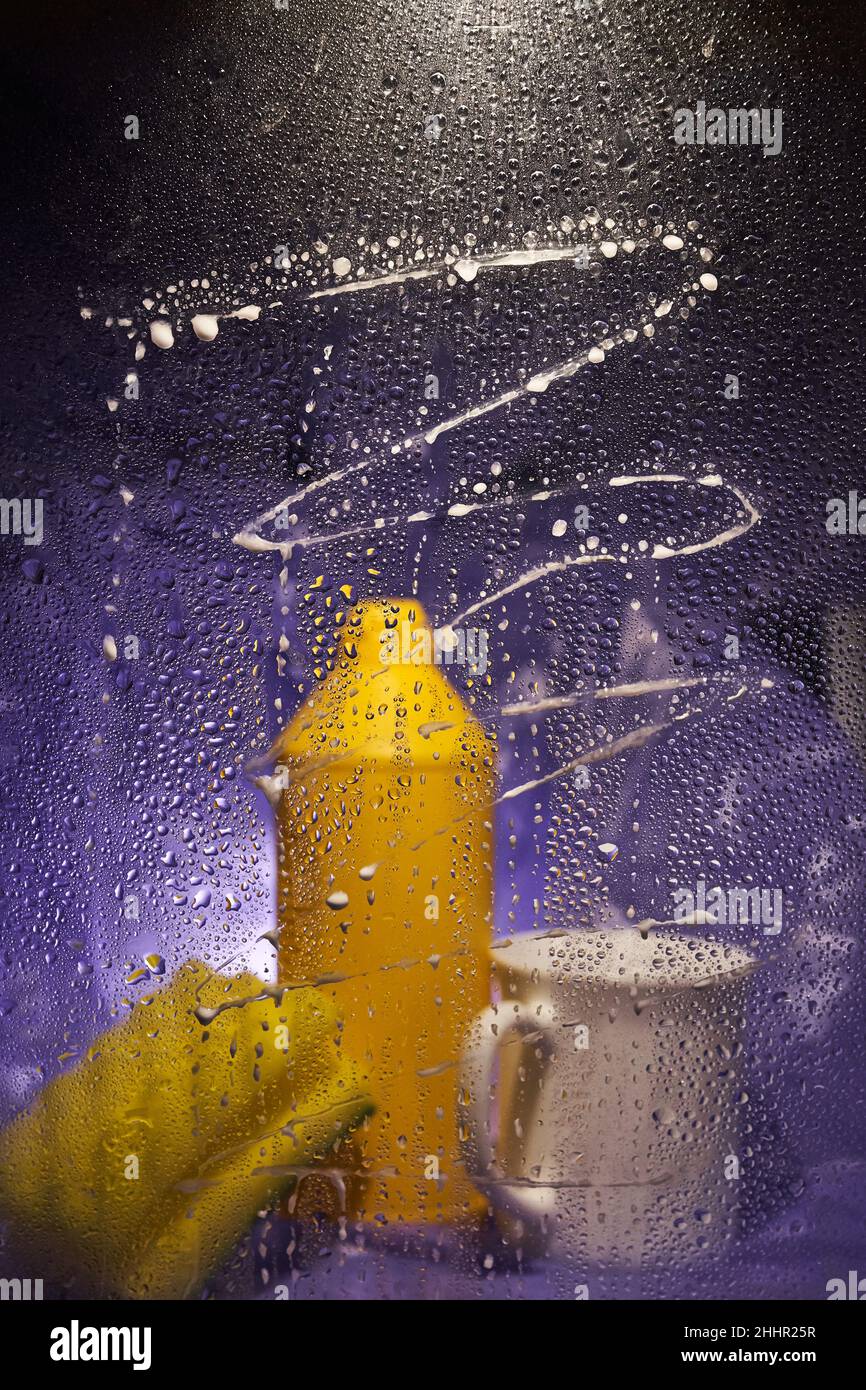Auf einem dunklen, fliederfarbenen Hintergrund. Nahaufnahme von Haushaltsreinigungsprodukten und Küchenzubehör. Blick durch schmutziges Glas. Hochwertige Fotos Stockfoto