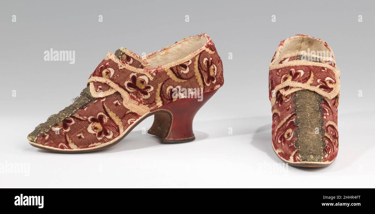 Schuhe 1732–59 Britische, robust zerfetzte Stoffe waren im späten 17th. Und frühen 18th. Jahrhundert eine gängige Wahl für die Schuhe aristokratischer Damen. Das auffällige, auffällige und ansprechende Textil dieses Paar Latchet-Schuhe sorgt durch die Kombination aus Samt und Metallic-Besatz für ein luxuriöses Gefühl. Obwohl der weiße Rand (Lederstreifen entlang der Vorderkante der Sohle) und der rote Absatz keine ungewöhnlichen Merkmale waren, machen sie hier eine besonders angenehme Abstimmung mit dem Stoff des Oberfl. Auch wenn es für moderne Augen vielleicht übertrieben war, war die breite Metallbandverkleidung auf dem Vamp ein Lieblingsdekor Stockfoto