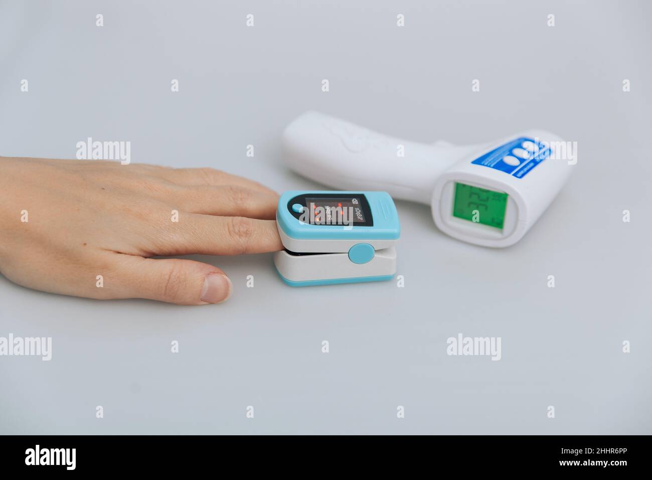Pulsoximeter und Thermometerpistole auf weißem Hintergrund. Messung der Sauerstoffsättigung, der Pulsfrequenz und des Sauerstoffgehalts. Isometrisches Infrarot-Thermometer Stockfoto