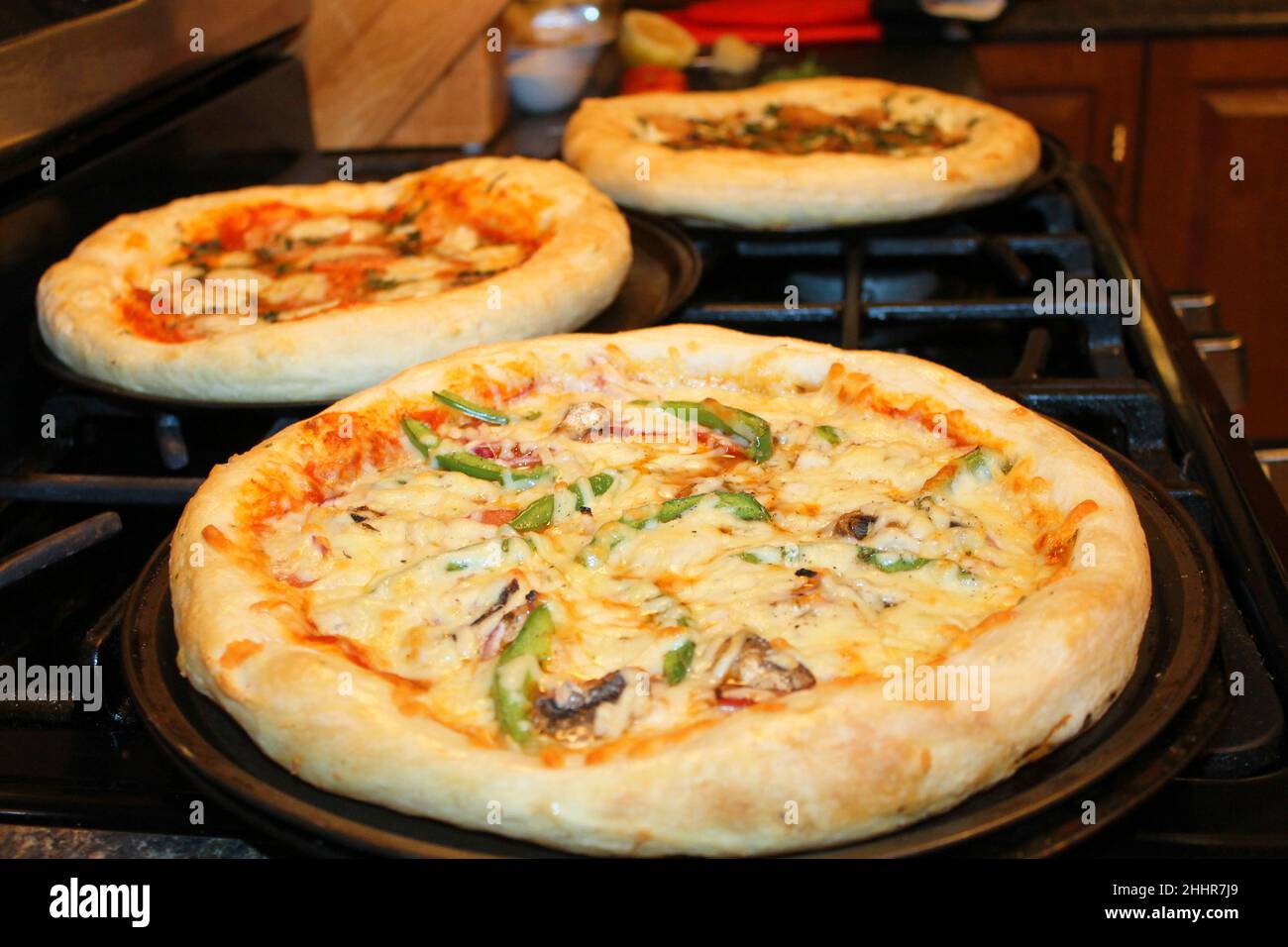 Drei gekochte Pizzen kühlen auf einem Herd. Stockfoto