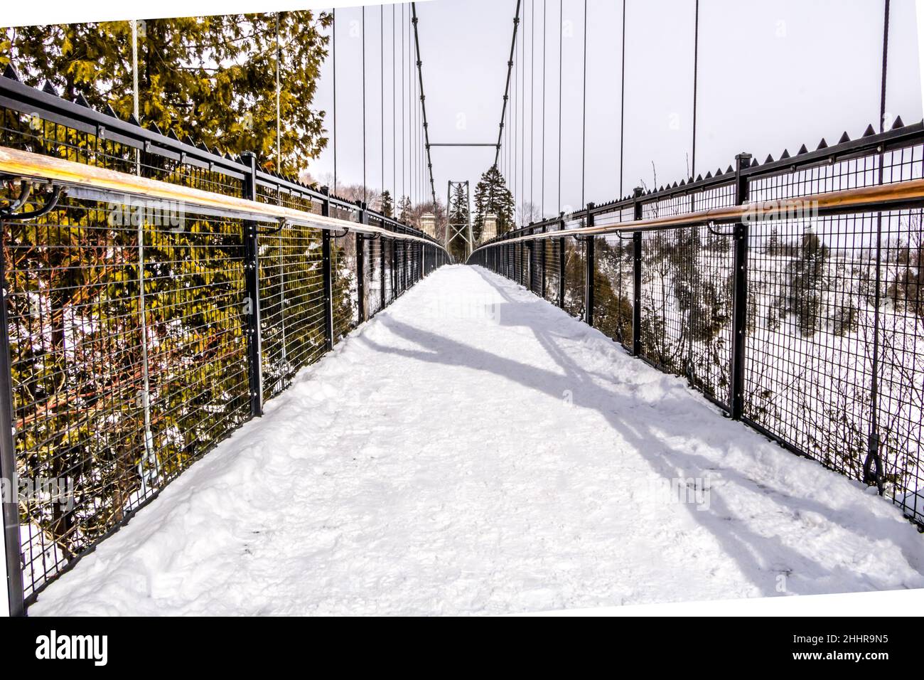 Schneebedeckte Hängebrücke über einem Wasserfall Stockfoto