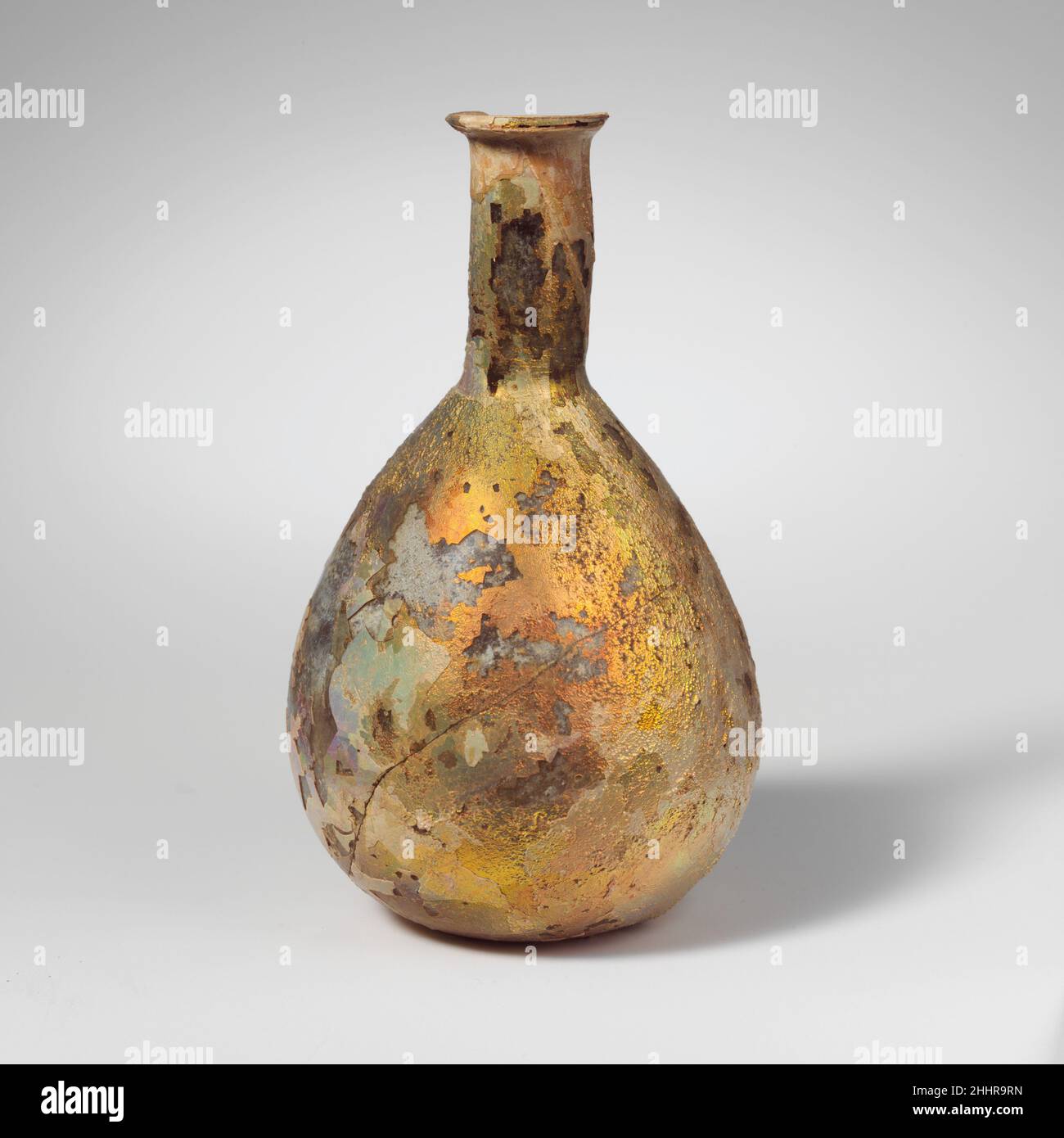 Parfümflasche aus Glas 1st–2nd Jahrhundert n. Chr. römisch farblos (?).kleiner, verdrehter Rand, mit abgeschrägter Außenlippe; zylindrischer Hals, mit Werkzeugen um den Boden herum; piriformaler Körper; abgerundeter Boden, in der Mitte flach.intakt, mit Ausnahme eines Teils des Randes und eines großen Riss im Körper; viele Blasen; tiefes Lochfraß und brillant schillernde Verwitterung. Parfümflasche aus Glas 239674 Stockfoto