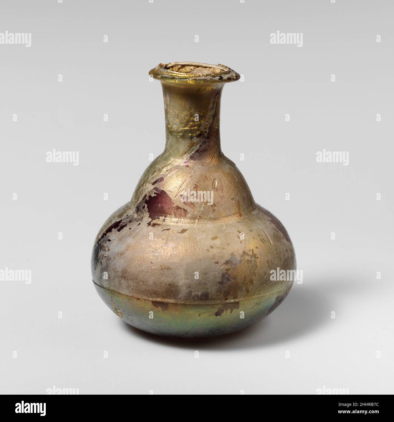 Parfümflasche aus Glas 1st. Jahrhundert n. Chr. Römische kleine ParfümbodenDurchscheinend hellblaugrün, mit violetten Streifen.Rand ausgeklappt, über und in, mit abgeschrägter Oberfläche; zylindrischer Hals, mit Werkzeugmarkierungen um die Basis; konvexe, schräge Schulter mit markanten Werkzeugmarkierungen unten; hockiger Knollenkörper; Leicht konkaver Boden.gebrochen und repariert um den Körper herum, mit einem gezackten Loch; Nadelstich Blasen; schwere Lochfraß, etwas dullend, und brillant schillernde Verwitterung.. Parfümflasche aus Glas 239767 Stockfoto