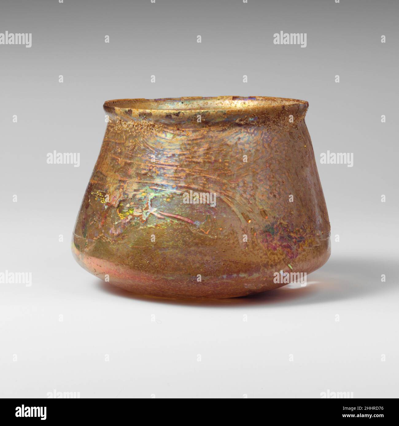 Glasbecher Mitte des 1st. Jahrhunderts n. Chr. römisch farblos mit hellem blaugrünem Farbton.abgeklopfter, unebener Rand; leicht gewölbter Kragen unter dem Rand; Seiten nach unten ausdehnend, dann scharf angewinkelt, um leicht konkaven Boden zu verbinden.Band aus schwachen, radabgeschrägten Linien am unteren Teil der Seiten über dem Winkel.intakt, außer Loch im Boden; Blasen und Blasstreifen; tiefes Lochfraß und brillant schillernde Verwitterung; Bodeneinbrüche im Inneren des Bodens.. Glasbecher 239879 Stockfoto