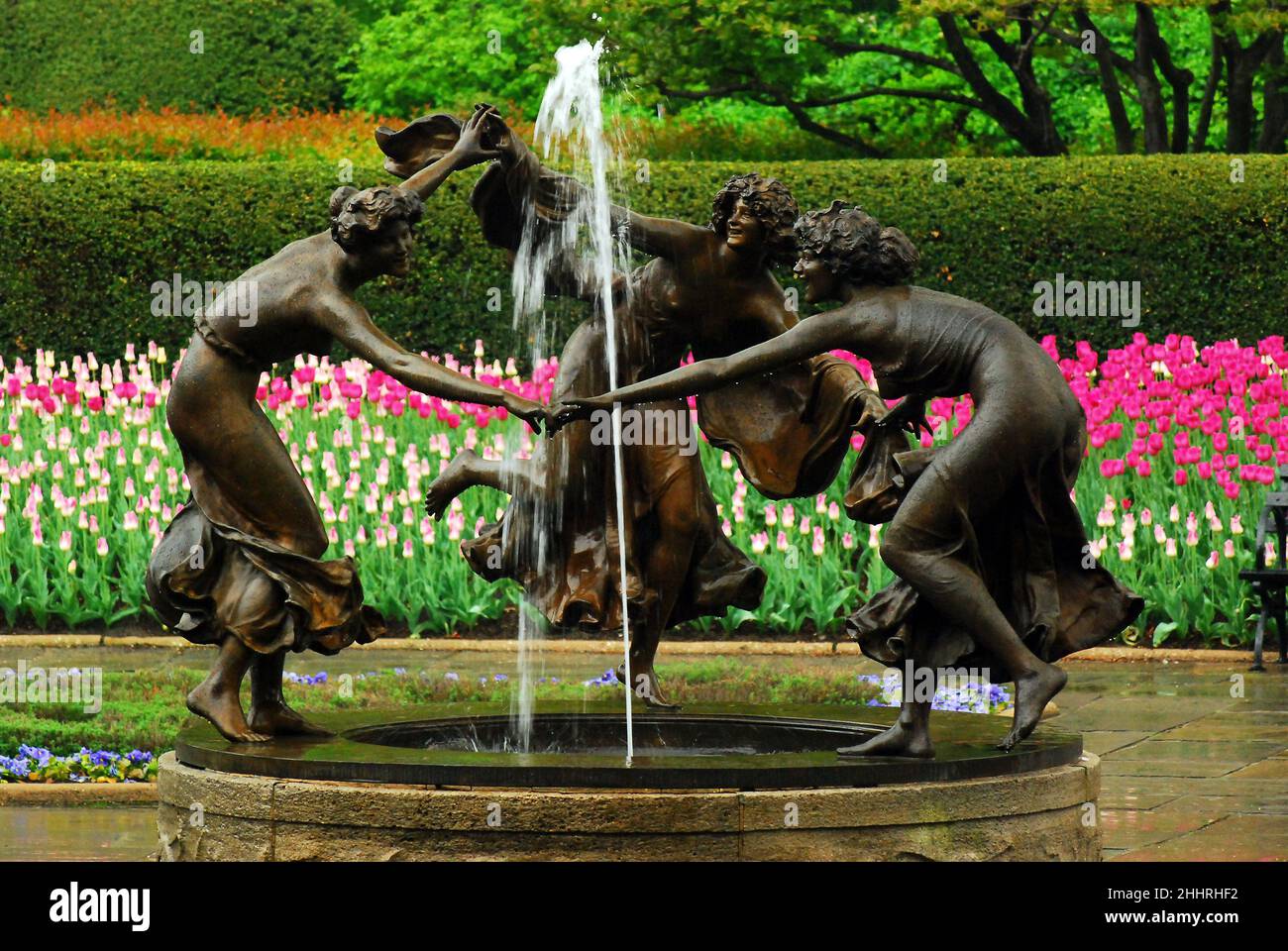 Tulpen blühen um drei tanzende Nymphen des Untermeyer Fountain im New Yorker Central Park Stockfoto