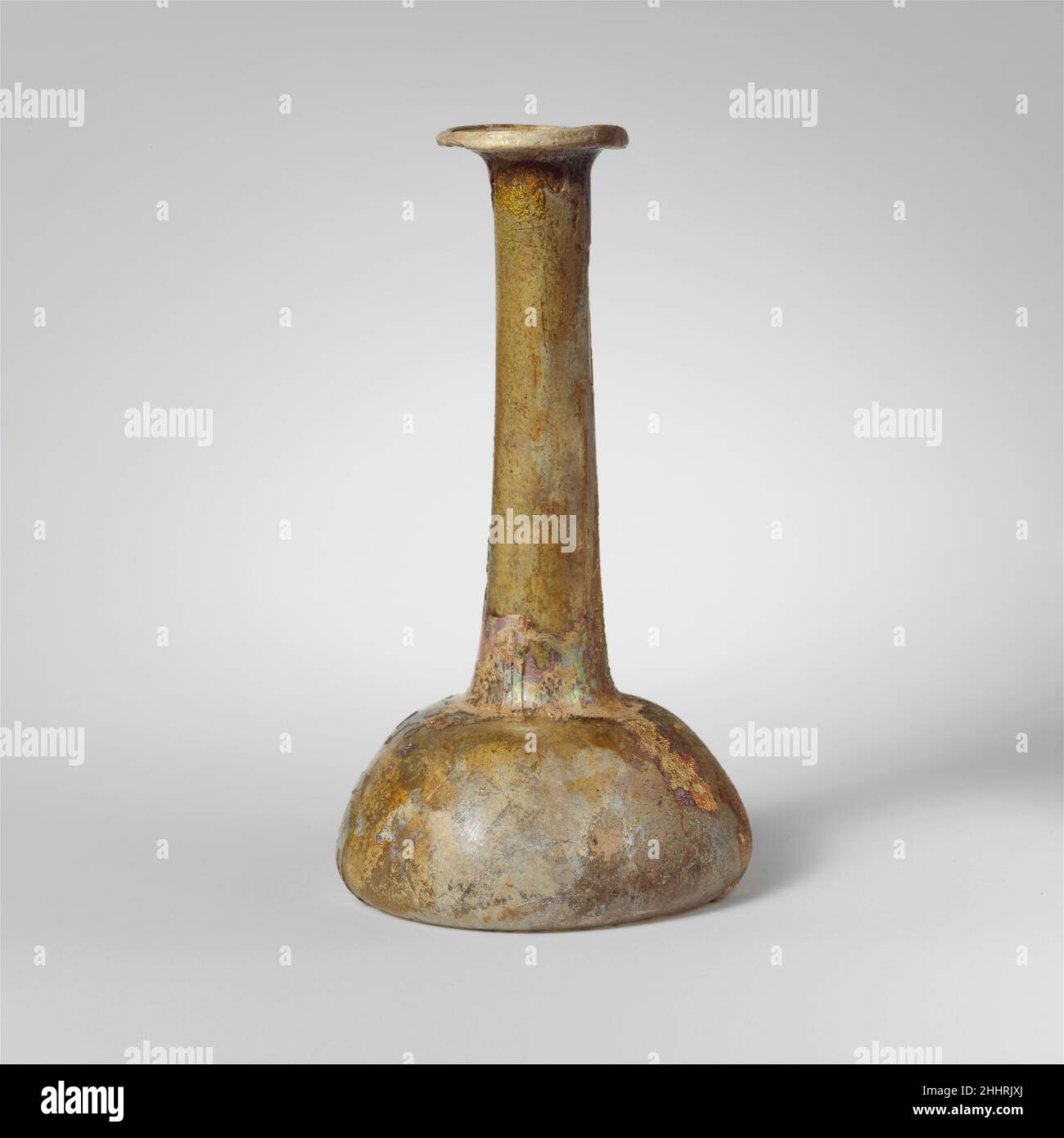 Parfümflasche aus Glas 2nd–3rd Jahrhundert n. Chr. römisch farblos mit hellblaugrünem Farbton. Unebener Rand, ausgeklappt, über und in, mit abgeschrägter Außenkante; breiter, abfackelter Mund; hoher zylindrischer Hals, sich nach unten ausdehnend mit Werkzeugmarkierungen um den Boden und auf kleiner horizontaler Schulter; konischer Körper mit konvexen Seiten; konkaver Boden.intakt; Viele Nadelstichtblasen; tiefes Lochfraß, Abstumpfen, Und brillant schillernde Verwitterung. Parfümflasche aus Glas 244586 Stockfoto