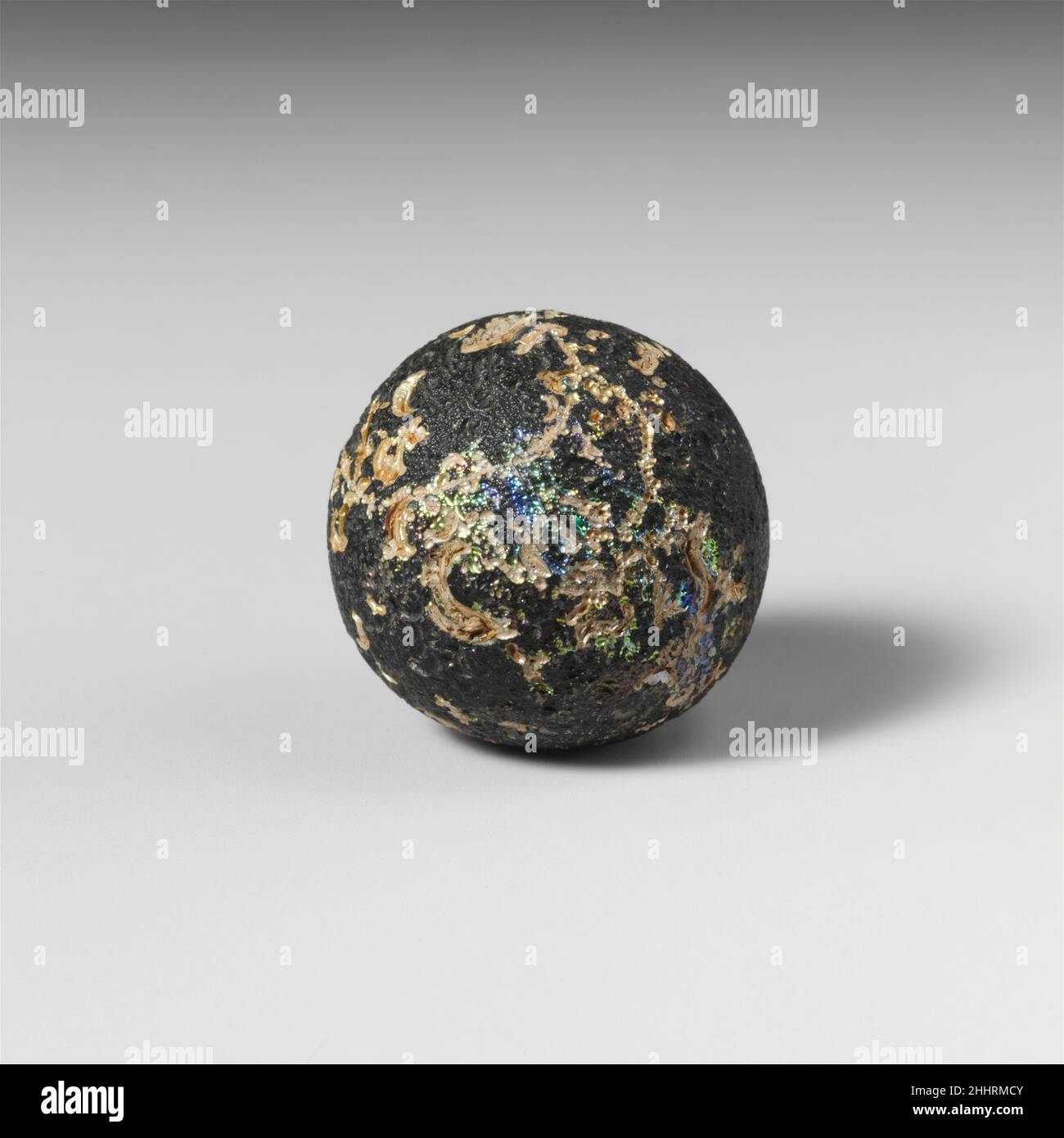 Glasmarmor 1st–4th Jahrhundert n. Chr. Roman Durchscheinend türkis grünlich blauVollflächige Kugel.zahlreiche kleine halbmondförmige Eindrücke in der Oberfläche, kombiniert mit einigen wenigen Kreisen und möglichen Buchstaben.intakt, aber mit inneren Rissen; taumelnd und streichelnd, mit Bereichen brillant schillernder Verwitterung. Marmor aus Glas 239913 Stockfoto