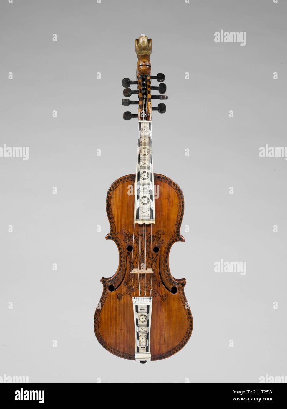 Hardanger Fiddle 1786 Norwegian die Hardanger Fiddle aus Westnorwegen hat eine Geigenform, verfügt aber über eine phantasievolle Schriftrolle, ein hochdekoratives Griffbrett und Saitenhalter, Tuschedesigns auf Vorder- und Rückseite und sympathische Saiten, die durch die Brücke und unter dem Griffbrett verlaufen. Isak N. Botnen (1669-1759) und sein Sohn Trond Botnen machten sowohl Standard-Geigen als auch Hardanger-Geigen. Hardanger Fiddle. Norwegisch. 1786. Holz, Perlmutt, Ebenholz, Knochen. Norwegen. Chordophon-Laute-gebeugt-unfrettiert Stockfoto