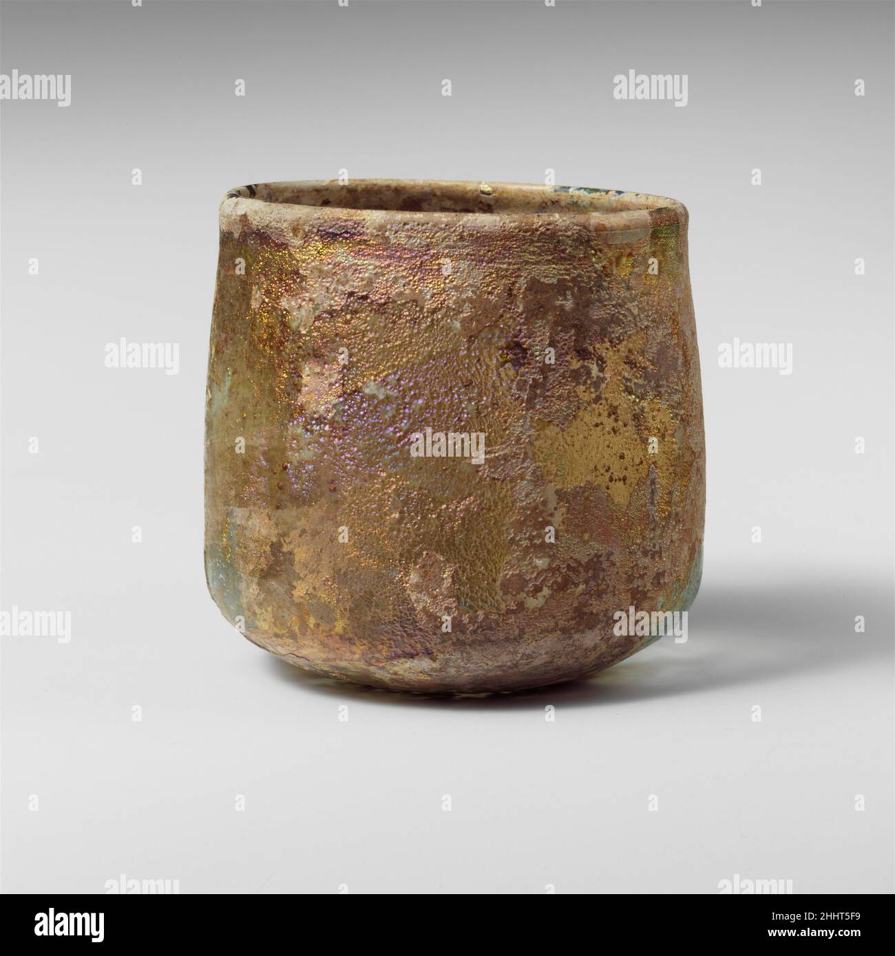 Glasbecher 2nd–3rd century A.D. römisch farblos mit blassblaugrüner Färbung. Verdicker, abgerundeter, vertikaler Rand mit Innenlippe; gerade Seiten leicht nach unten ausdehnend, dann in scharfem Winkel nach unten gedreht mit spitz zulaufendem tritt bei center.Complete, aber Loch in der Seite (von der Devitrifikation); Nadelstich Blasen und Blasen; Stumpfes, tiefes Lochfraß, brillantes Schillern und weißliche Verwitterung. Glasbecher 244614 Stockfoto