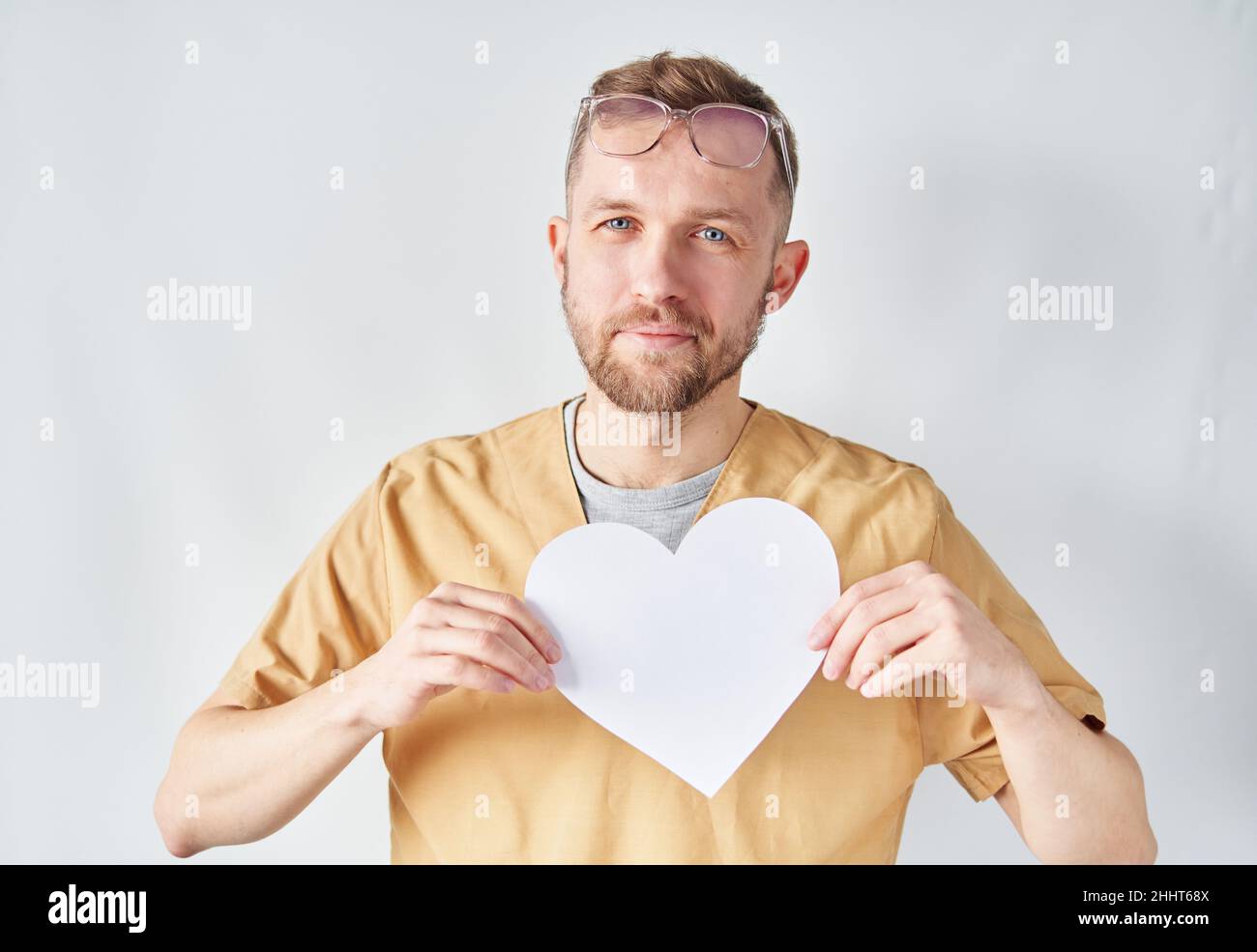 Medizinisches Gesundheitswesen Geschäft und Ärztedienst. Porträt eines männlichen Arztes oder einer Krankenschwester mit weißer Papierherzform. Professioneller kaukasischer Arzt oder medizinische und medizinische Versorgung im Krankenhaus. Hochwertige Fotos Stockfoto