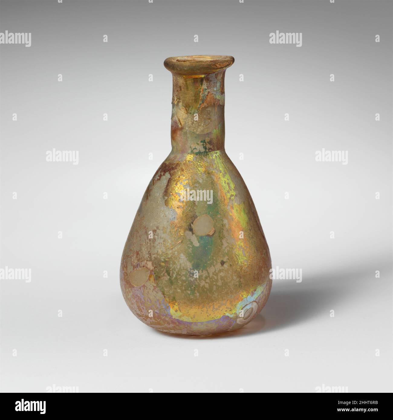 Parfümflasche aus Glas 1st Jahrhundert n. Chr. römisch farblos.Rand ausgeklappt, über und in, mit ungleichmäßiger abgeflachte obere Oberfläche; zylindrischer Hals, mit eingedrehtem Einrücken um die Basis; piriformer Körper; abgerundeter Boden, flach in der Mitte.gebrochen und repariert, mit fehlenden Stücken um den Körper und auf dem Boden; Nadelstich Blasen und Blasen Streifen; Lochfraß und brillant schillernde Verwitterung, mit einigen Bodenverkrustungen auf der Innenseite des Halses.. Parfümflasche aus Glas 244631 Stockfoto