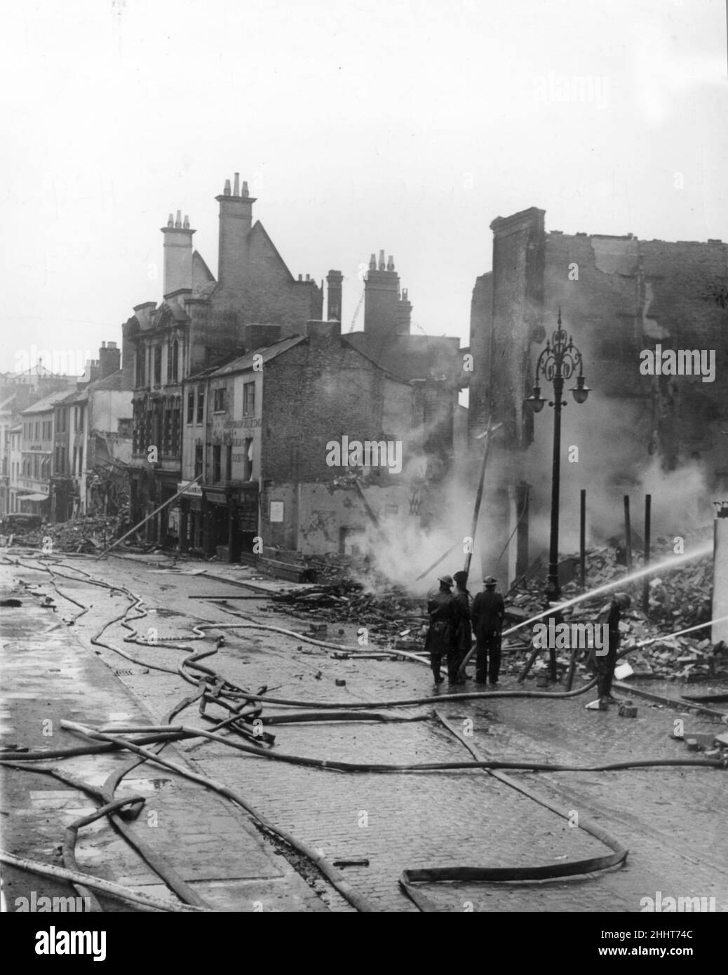 Feuerwehrleute warten auf Häuser, die noch in der Hertford Street in Coventry brennen, nachdem die Stadt während des Zweiten Weltkriegs von der deutschen Luftwaffe bei einem Luftangriff angegriffen wurde. 10th. April 1941. Stockfoto