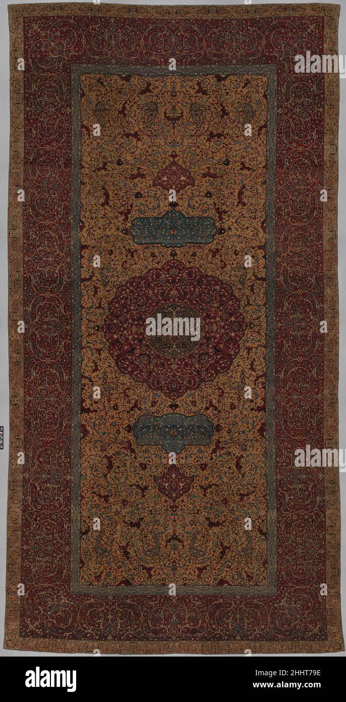 Der Anhalt-Medaillon-Teppich wohl erste Hälfte des 16th. Jahrhunderts der hervorragende Zustand und die ungewöhnlichen Farben machen diesen Teppich zu einem einzigartigen Beispiel für die Teppichproduktion während der Safavid-Zeit im Iran. Das gelbe Feld, das bei Teppichen dieser Art selten zu sehen ist, macht es zu einer ungewöhnlichen Variation eines klassischen Designs. Das zentrale Medaillon, rollende Reben (Arabeske) und Pfauen auf dem Feld sind alle gemeinsame Merkmale von Safavid Teppichen. Die Arabeske Designs weisen Parallelen zu persischen Fliesenrepezments aus dem 16. Jahrhundert auf, während das zentrale Medaillon-Design dem zeitgenössischen Buchcover ähnelt, was auf t hindeutet Stockfoto