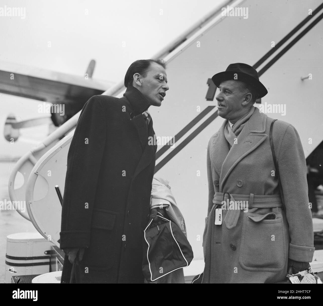 Sänger Frank Sinatra hier mit dem Sunday People-Journalisten Arthur Helliwell, der am Londoner Flughafen einen TWA-Flug nach New York besteigen wird. Ca. Dezember 1952 Stockfoto