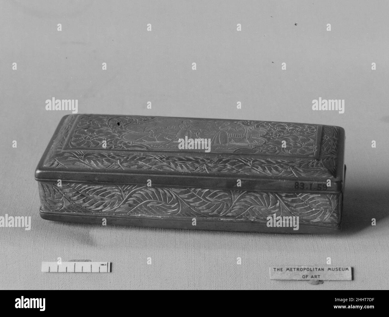 Tabakdose 17th Jahrhundert Niederländisch oder Flämisch die Schachtel ist rechteckig, ihr Deckel und ihre Unterseite sind jeweils mit einer kunstvollen Messingkartusche versehen. Die Kartusche auf dem Deckel hat eine Szene, die fast identisch mit der auf 57.108.9 ist, mit einigen kleinen Variationen im Hintergrund und in der Kleidung.die Szene auf der Unterseite ähnelt ebenfalls der auf der Unterseite von 57.108.9; nur die Pose des Paares variiert. Die Inschriften auf Deckel und Unterseite sind die gleichen wie auf 57.108.9, und die Kartuschen sind auch von Blattrollen umgeben.die Ränder sind ausgekleidet, die Kanten sind geformt, und Blattrollen schmücken die Ränder und Stockfoto Tabakdose 17th Jahrhundert Niederländisch oder Flämisch die Schachtel ist rechteckig, ihr Deckel und ihre Unterseite sind jeweils mit einer kunstvollen Messingkartusche versehen. Die Kartusche auf dem Deckel hat eine Szene, die fast identisch mit der auf 57.108.9 ist, mit einigen kleinen Variationen im Hintergrund und in der Kleidung.die Szene auf der Unterseite ähnelt ebenfalls der auf der Unterseite von 57.108.9; nur die Pose des Paares variiert. Die Inschriften auf Deckel und Unterseite sind die gleichen wie auf 57.108.9, und die Kartuschen sind auch von Blattrollen umgeben.die Ränder sind ausgekleidet, die Kanten sind geformt, und Blattrollen schmücken die Ränder und Stockfoto