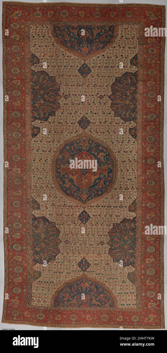 Ushak Medallion Teppich auf weißem Grund erste Hälfte des 17th. Jahrhunderts Medallion Ushak Teppiche haben in der Regel ein rotes oder blaues Feld mit einem floralen Spalier oder Blattranken, zentralen Medaillons und einem Rand mit Palmetten auf einer Blumen- und Blattrolle und Pseudo-Kufic-Zeichen verziert. In diesem (teilweise restaurierten) Beispiel wird ein typisches weißes Feldmuster mit dem Medallion Ushak zu einer neuen Kategorie osmanischer Teppiche kombiniert. Sein dreifaches, gewelltes Doppelstreifenmuster, genannt çintamani, erscheint häufig in der osmanischen Kunst aus dem 16. Jahrhundert auf Fliesen, Gemälden, Bucheinbänden, Stockfoto