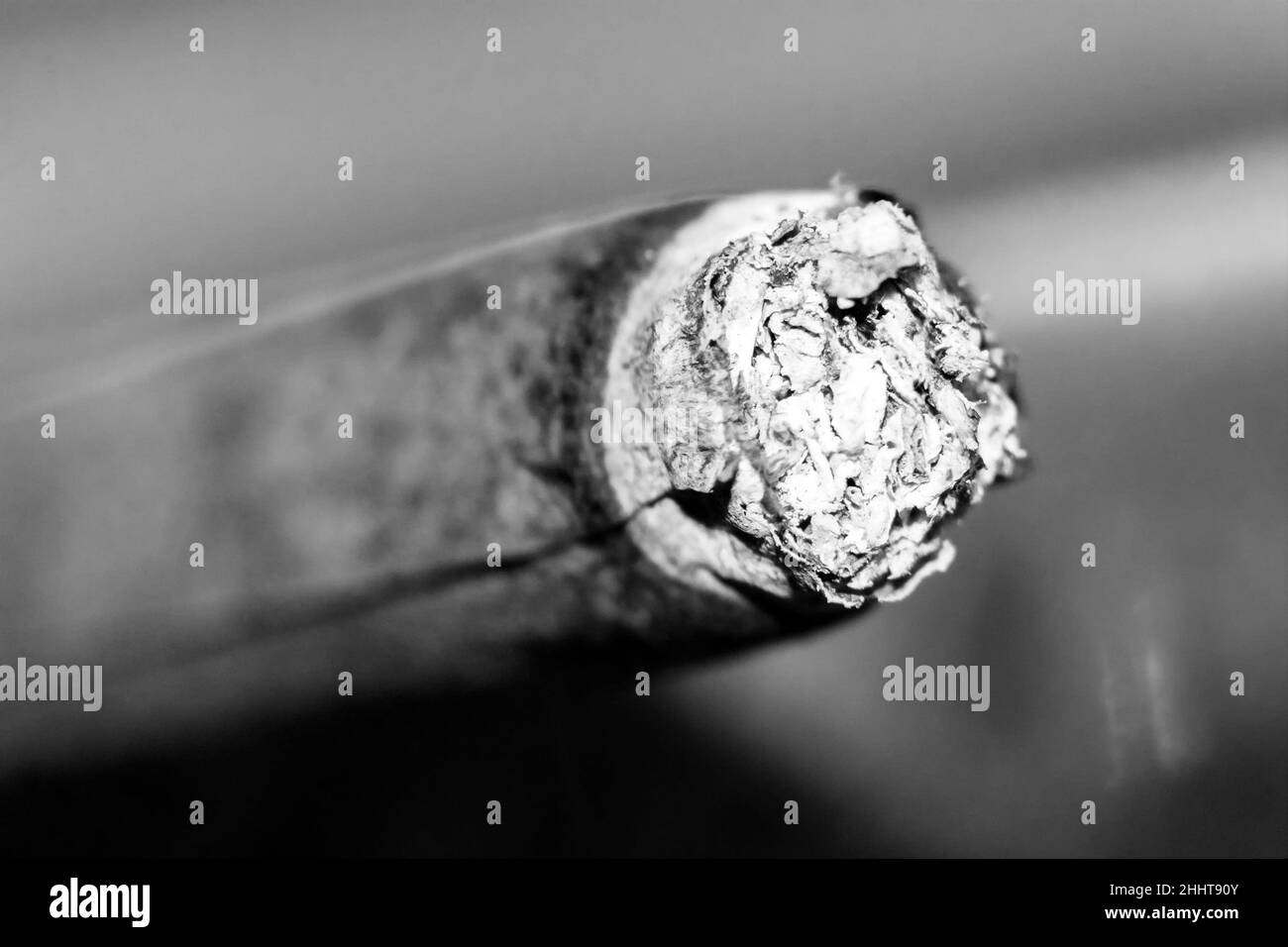 Schwelende braune Zigarette, Asche, Makroaufnahme mit unscharfem Hintergrund Stockfoto