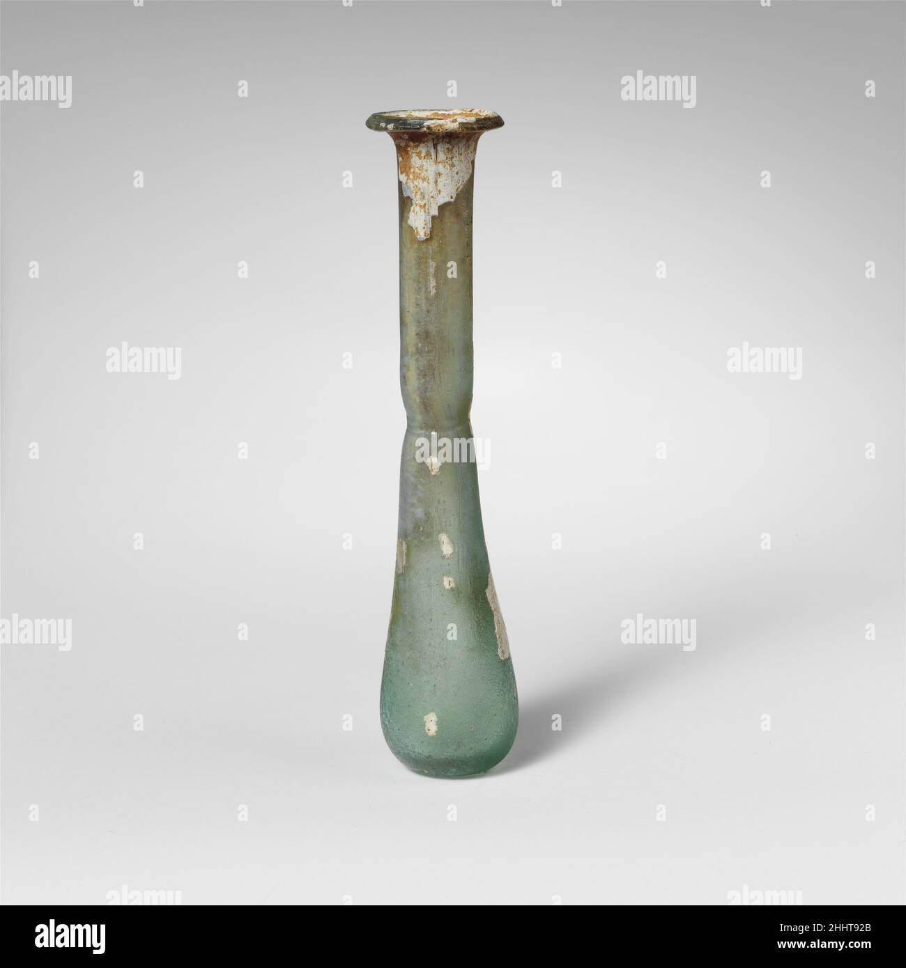 Parfümflasche aus Glas 1st–2nd Jahrhundert n. Chr. Roman sehr schlankes Unguentarium.Durchscheinendes blaugrün.feiner Rand ausgeklappt, über- und eingefaltet; flackernder Mund; zylindrischer Hals mit eingedornter Einkerbung um die Basis; länglicher ovoider Körper; kleiner, konkaver Boden mit Spuren von Pontil-Narbe.intakt; Nadelstrüberblasen und durchgeblasene Streifen; Abstumpfen, Lochfraß und Flecken schillernder Verwitterung auf der Außenseite, Bodenverkrustungen und weißliche emaillartige Verwitterung auf der Innenseite des Halses. Parfümflasche aus Glas 244680 Stockfoto