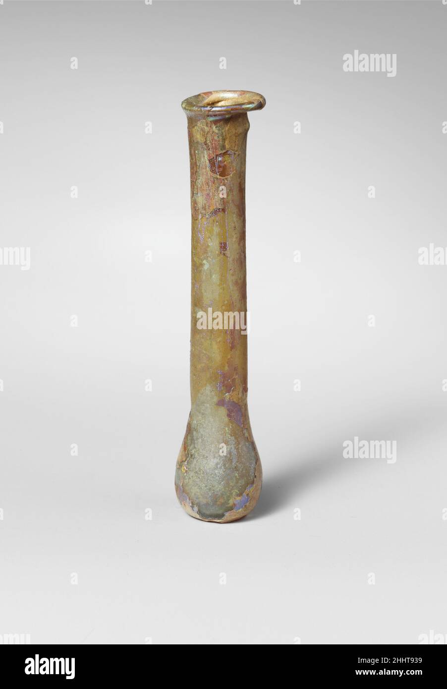 Parfümflasche aus Glas 1st–2nd Jahrhundert n. Chr. römisch farblos mit blassblaugrünem Farbton. Schräge Kante, ausgeklappt, über und in, und ungleichmäßig auf eine Seite gedrückt; hoher zylindrischer Hals; kleiner, hockiger, kugelförmiger Körper; Eingeschobene Unterseite mit Spuren von Pontil-Markierung. Intakt; Nadelstichtblasen; Abstumpfen, Lochfraß und Flecken brillanter irisierender Verwitterung auf der Außenseite, Bodenverkrustungen und cremig-brauner Verwitterung auf der Innenseite. Parfümflasche aus Glas 244689 Stockfoto