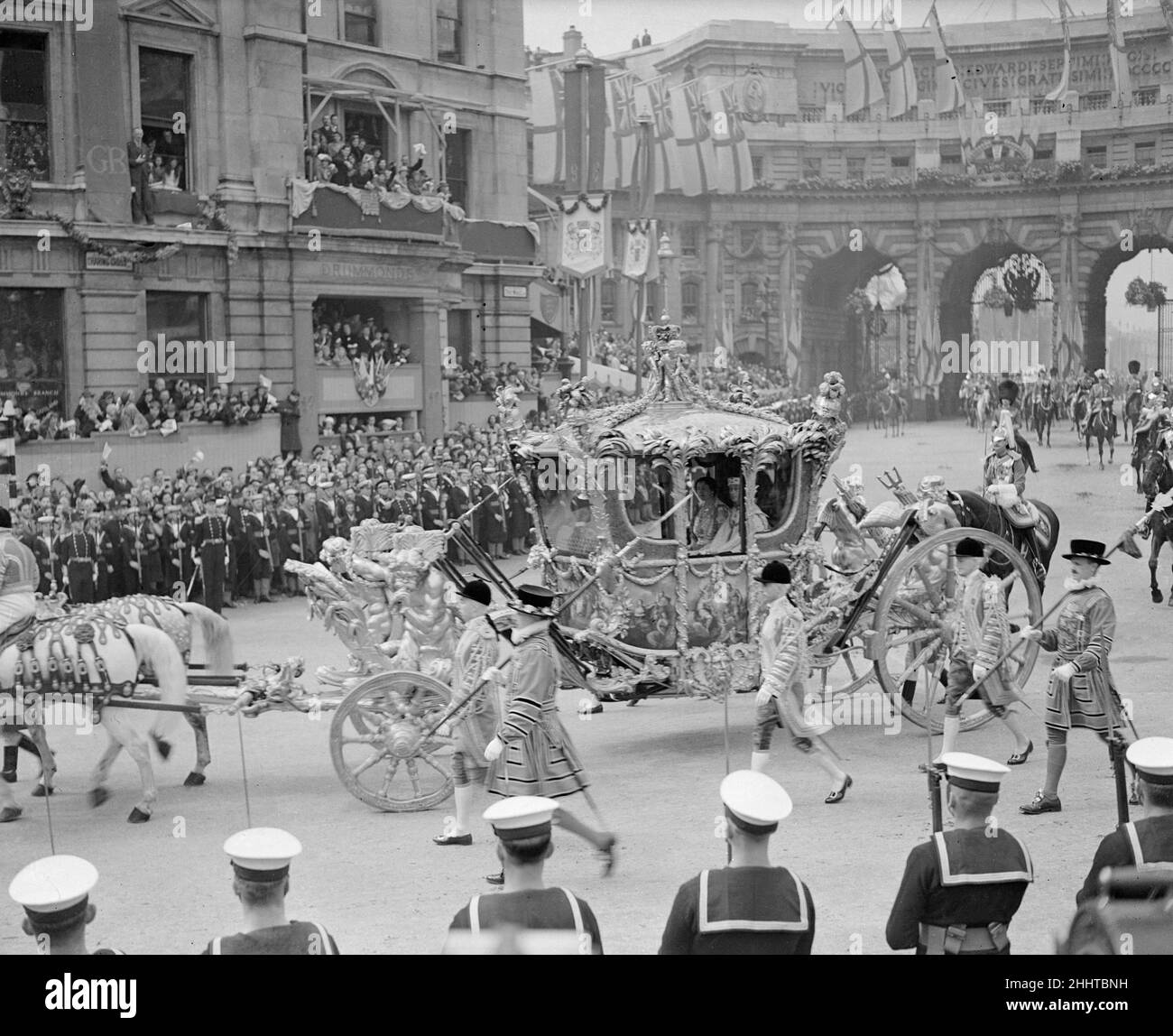 Krönung von König Georg VI. Der goldene Staatsbus mit König George VI fährt durch den Amiralty Arch in der Mall, während Tausende von Menschen von der Straßenseite aus jubeln. 12th Mai 1937. Stockfoto