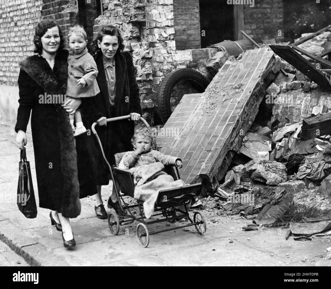 Frau Applegate (links) und Frau King mit Kindern, die an einem bombardierten Gebäude vorbeigehen. September 1941. Stockfoto