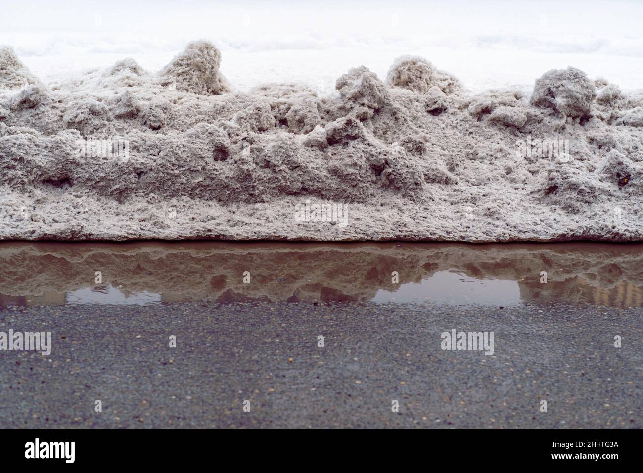 Schlammiger Schnee auf der Seite einer asphaltierten Straße Stockfoto