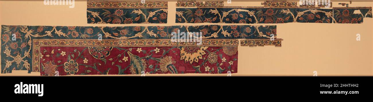 Fragmente eines Teppichs Mitte des 17th. Jahrhunderts der Stapel dieses Teppichs aus Pashmina-Wolle, die aus dem Unterwolle der Himalaya-Bergziege gewonnen wurde, ist auf einem Seidenfundament geknotet. Eine hohe Knotenzahl, die durch die Verwendung dieser luxuriösen Materialien erreicht wird, ermöglicht ein Design von scharf-detaillierten Verflechtungen von Blumen und Reben. Obwohl sich das Gesamtmuster der Arbeit auf das persische Teppichdesign bezieht, sind das rote Feld und das Vorhandensein von Lotusblumen an der Grenze unverkennbar indisch. Fragmente eines Teppichs 446640 Stockfoto