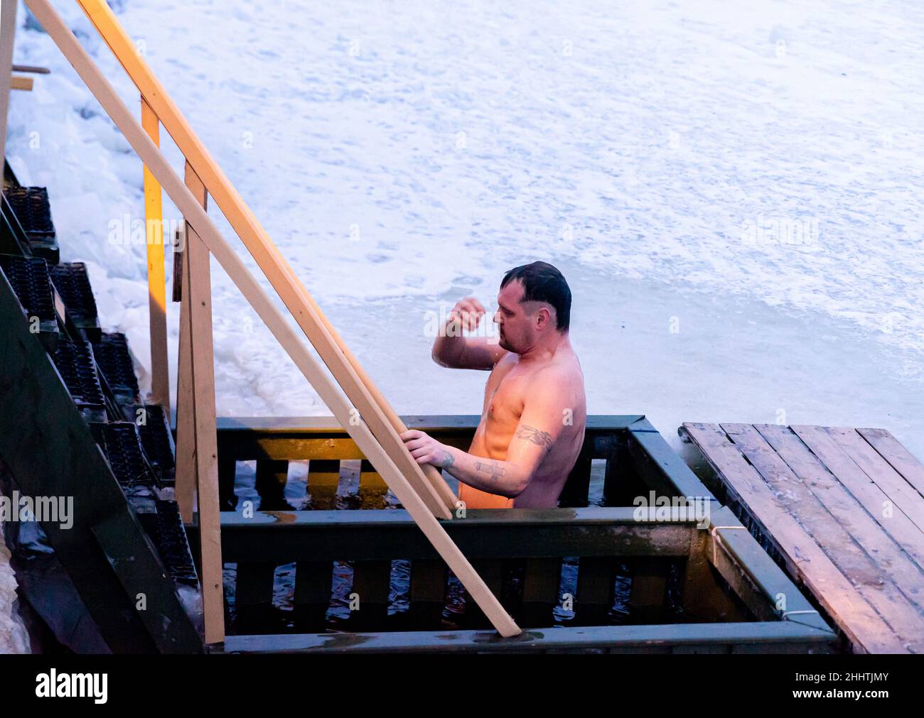 Ein Mann überquert sich selbst, während er in das eiskalte Wasser taucht, als orthodoxe Epiphanie-Taufe im Fluss Neva, St. Petersburg, Russland, badete Stockfoto