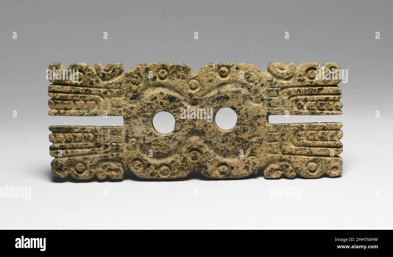 Anhänger 12th–14th Jahrhundert Mixtec dieser flache, rechteckige Anhänger zeigt vier Profilgesichter mit langen, toothy Schnauzen an jeder Ecke, verbunden mit welligen, gepunkteten Körpern, die durch zwei runde Löcher getrennt sind. Die Kreaturen können Schlangen, Katzen oder Krokodile oder eine Kombination dieser Tiere darstellen. Alle waren in Mesoamerika häufig mit Wasser und Fruchtbarkeit assoziiert. Die Zusammensetzung ist beidseitig symmetrisch, sowohl auf der horizontalen als auch auf der vertikalen Achse. Zwei kleine Löcher an der Oberseite im Rücken sind für die Aufhängung.der Anhänger ist in einem Stein von grüner Farbe gearbeitet, ein Farbton symbolisch für Wasser, Fruchtbarkeit und Leben. Gre Stockfoto