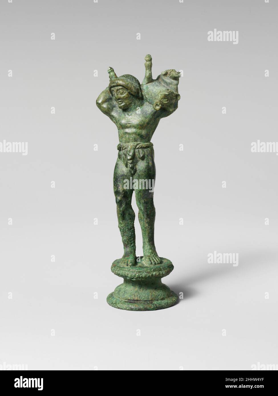 Bronzestatuette eines jungen Menschen, der ein Schwein trägt, Anfang des 5th. Jahrhunderts v. Chr. etruskische Statuen von Jugendlichen oder Göttern, die Tiere zum Opfer tragen, sind in der griechischen Kunst üblich, aber in den Etruskern relativ selten. Diese Statuette, die in ihrer Darstellung anatomischer Details sehr raffiniert war, war einst das Finale für einen Kandelaber. Bronzestatuette eines Jungen, der ein Schwein trägt 247510 Stockfoto
