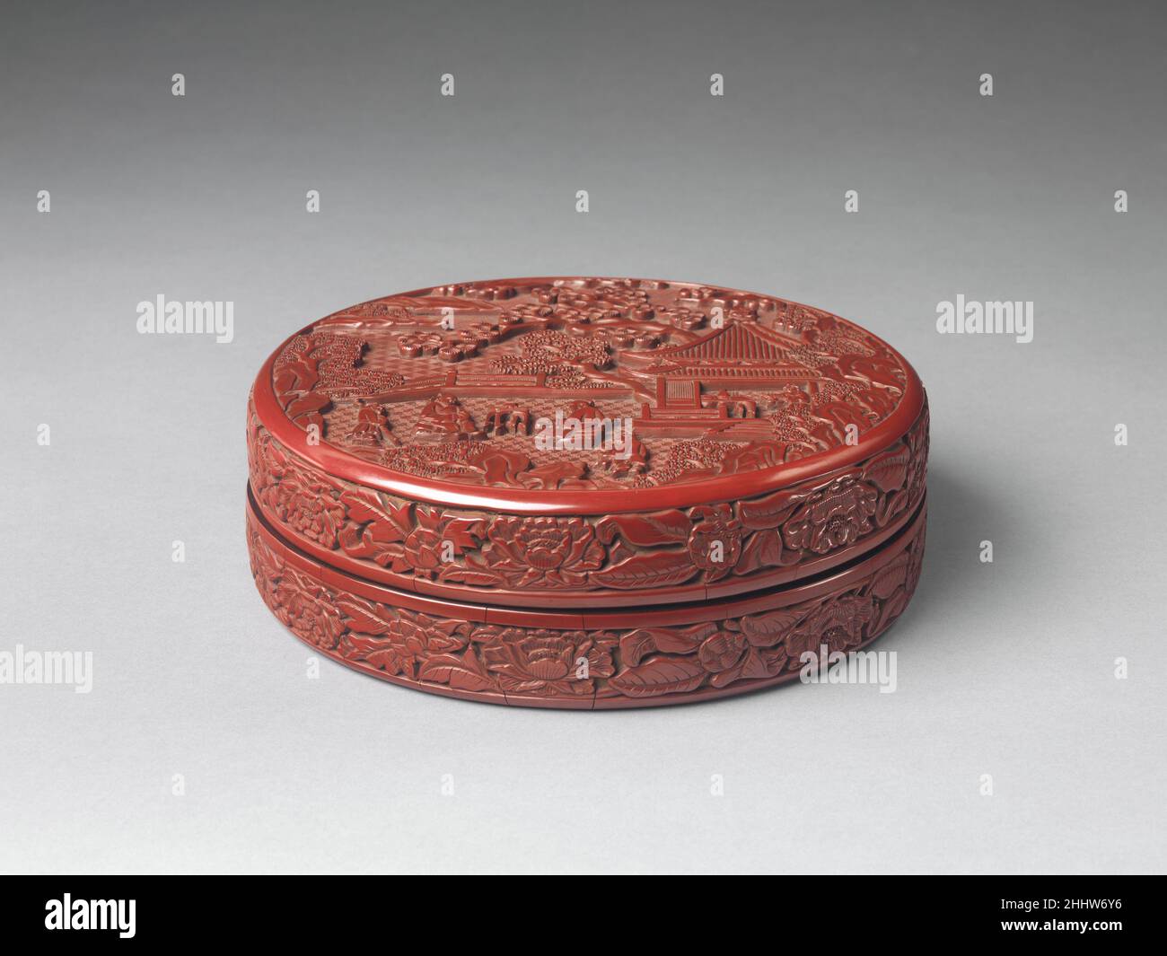 Box mit Szene einer Zither (qin), die sich 1403–1424 China versammelt auf dem Deckel dieser Box entspannen sich zwei sitzende Männer auf einer Veranda mit Blick auf ein Gewässer. Einer spielt die chinesische Zither (qin), während der andere zuhört. Ein Trio von Anwesenden, einer davon im nahegelegenen Pavillon, genießt ebenfalls die Musik. Szenen, die den kultivierten Lebensstil und die künstlerischen Fähigkeiten der wissenschaftlichen Klasse darstellen, wurden nach dem vierzehnten Jahrhundert in der chinesischen Malerei und dekorativen Kunst allgegenwärtig. Box mit Szene einer Zither (qin) Versammlung 40219 Stockfoto
