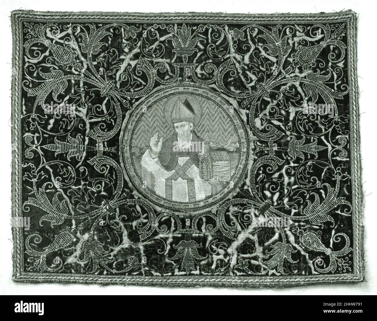 Roundel 15th und 17th Jahrhundert Italienisch oder Spanisch Diese Roundel aus dem 15. Jahrhundert, zusammen mit drei anderen aus der Sammlung Lehman (1975,1.2441, 1975,1.2442, 1975,1.2443), wurde auf rechteckige Tafeln aus dunkelrotem Samt appliziert, bestickt und in durchgehendes Strapwork gehütet, das Fleur-de-Lis- und Blattmuster aus dem 17. Jahrhundert formte. Zwei der Rechtecke, die mit goldfarbenem Metallband versehen waren, wurden direkt an einer gepolsterten Couch befestigt; die anderen beiden wurden zu Kissen gemacht, ohne Zweifel für dieselbe Couch. Jeder der Rundungen enthält eine Halbfigur. Alle vier Figuren enthalten Modelle Stockfoto