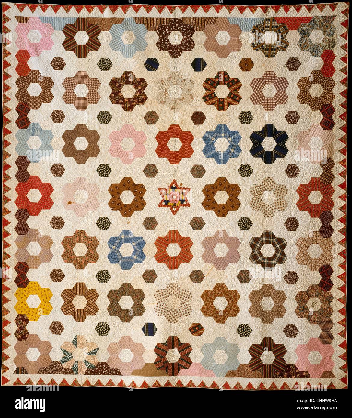 Quilt-, Hexagon- oder Honeycomb-Muster 1846 Rebecca Davis die Oberseite dieses Quilts besteht aus Sechsecken aus bunten und gemusterten Stoffen, die typisch für die 1840s sind, darunter einige Regenbogendrucke. Die Sechsecke sind etwa zwei Zoll pro Seite, mit Ausnahme eines kleinen sechszackigen Sterns in der Mitte, der aus einem halben Zoll pro Seite Sechsecke besteht. In den bedruckten Stoffsechsecken gibt es Quilting in parallelen diagonalen Linien und in verschiedenen Blumen- und Sternformen in den weißen Baumwollsechsecken. Die Steppdecke hat einen einfarbigen weißen gewebten Baumwollrücken und Wattebausch. Quilt-, Hexagon- oder Wabenmuster 13904 Stockfoto