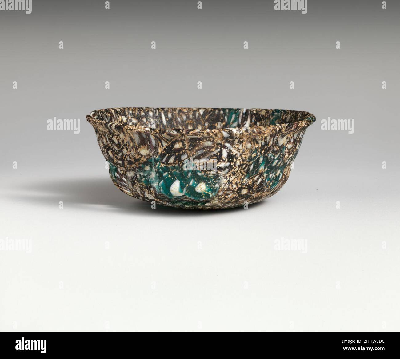 Mosaikglas-Schale Ende 1st. Jahrhundert v. Chr.–Anfang 1st. Jahrhundert n. Chr. Roman Durchscheinendes Purpur, transluzent türkisblau und opakes Weiß.ausgespielter abgerundeter Rand; leicht konvex abfallende Seite über horizontalem Einzug, dann eingebogenes Mosaikmuster bottom.Composite aus unregelmäßigen Abschnitten von zwei Stöcken: Einer in einem violetten Boden mit weißen Punkten; Die andere in türkisblau mit weißen Punkten.auf der Außenseite, kreisförmige Nut in Boden geschnitten.gebrochen und repariert mit mehreren großen Löchern; taumeln, Lochfraß, und schwach schillernde Verwitterung.. Mosaikglasschale 250728 Roman, Mosaikglasschale, Ende 1st. Jahrhundert Stockfoto