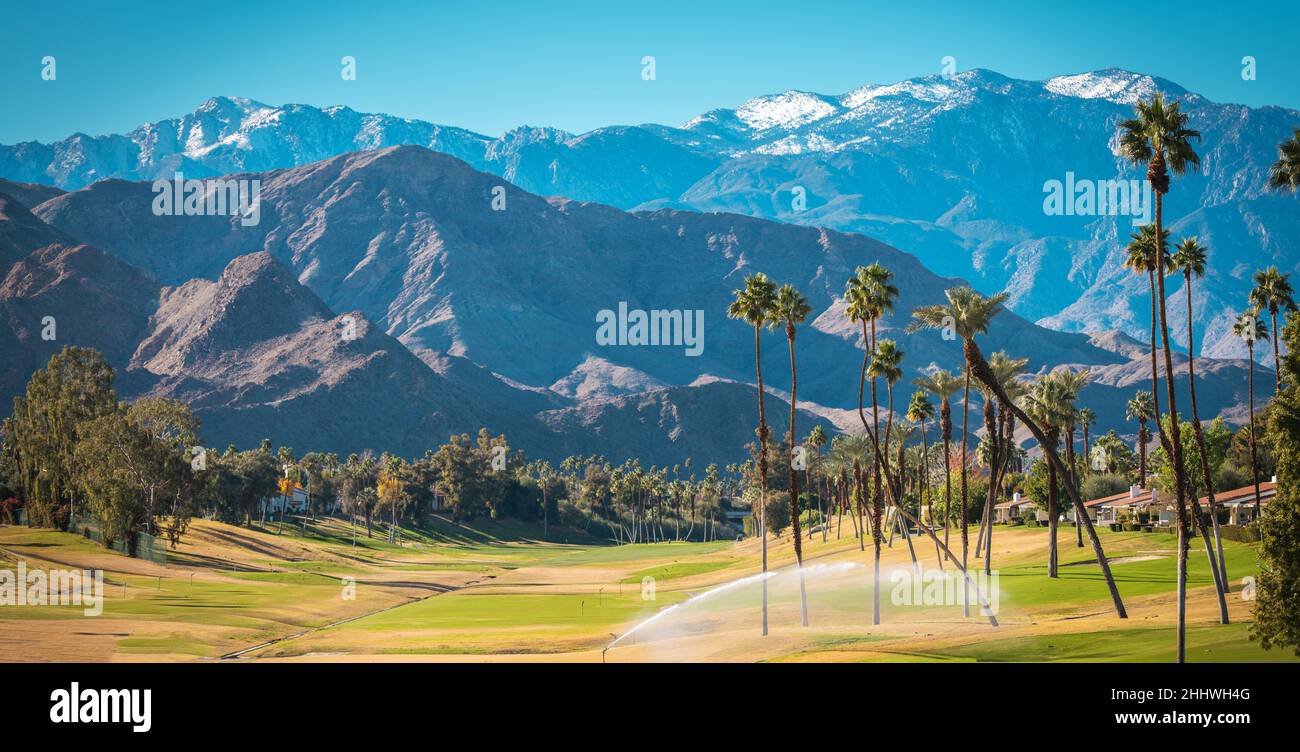 Sonnige, warme Winterzeit im Coachella Valley der Palm Desert. Golfplätze, Palmen und Berge mit frischem Schnee bedeckt. Erholung in Südkalifornien Stockfoto