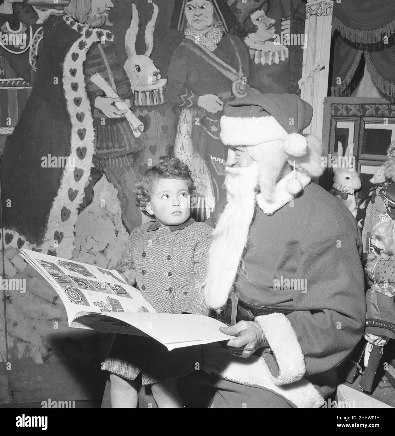 Vater Weihnachten hat hier gesehen, wie er mit einem jungen Kunden im Co-op-Geschäft in Edgware, London, sein unartiges oder schönes Buch durchsah. Januar 14th 1955 Stockfoto