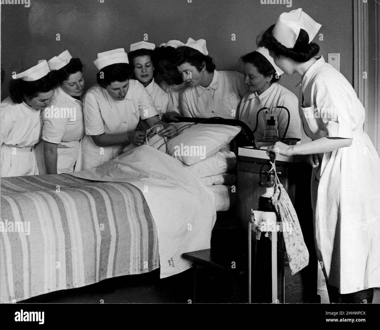 Krankenschwestern des staatlichen Krankenhauses lernen, Sauerstoff durch spektrbare Rahmen zu adminisyer. Zum Zweck des Trainings verwenden sie eine Puppe, an deren Nase Schläuche befestigt sind. Die Akteuten von sechs Nationalitäten erhalten grundlegende Kenntnisse über ihre Aufgaben in einem der neun Krankenhäuser, die von dem neuen Nationalen Gesundheitsprogramm der Central Preliminary Training School in Hadley Common, Hertfordshire, übernommen werden. 20th. Februar 1948. Stockfoto