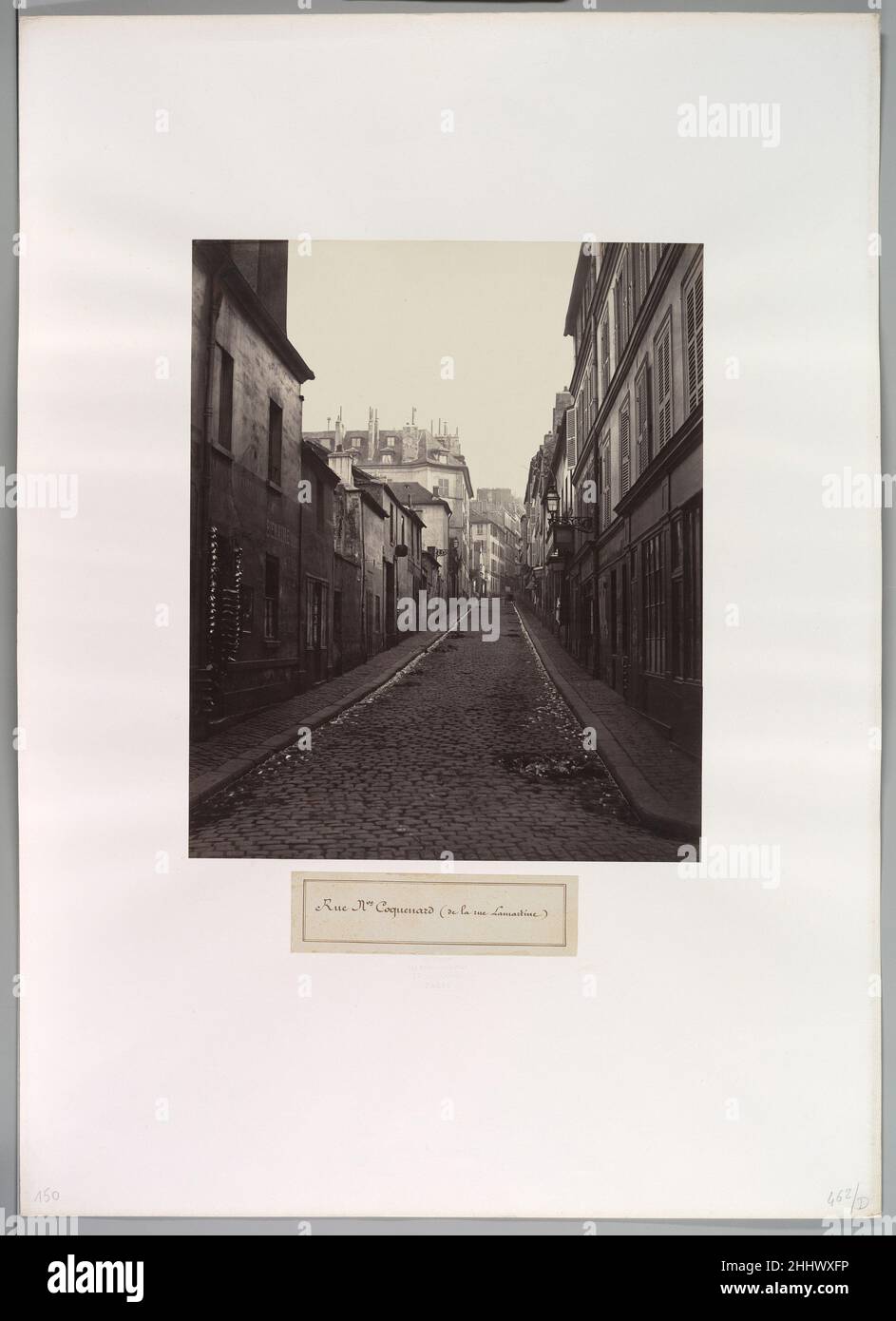 Rue Neuve-Coquenard (aus der Rue Lamartine) 1870s Charles Marville French Marville wurde als Maler und Illustrator ausgebildet, begann 1851 zu fotografieren und wurde 1862 zum „Fotografen der Stadt Paris“ ernannt. Im Dienste Napoleons III. Fotografierte er das umfangreiche Abriss- und Bauprogramm von Baron Haussmann. Obwohl er die moderne Stadt – ihre eleganten Straßenlaternen, Morris-Säulen und utilitaristischen Pissoirs – dokumentierte, die das Alte ersetzte, ist er am besten für seine detaillierten Ansichten der malerischen, unheilvollen Stadtteile bekannt, die zur Zerstörung bestimmt sind. Rue Neuve-Coquenard (von der Rue La Stockfoto