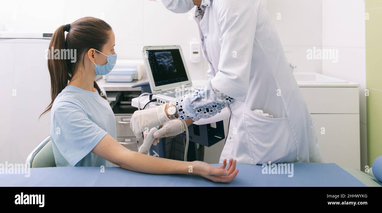 Arzt, der den Ultraschall an der Hand macht, Nahaufnahme. Der Arzt zeigt dem Patienten Ultraschallergebnisse. Medizinische Ultraschalluntersuchung. Rehabilitation Stockfoto