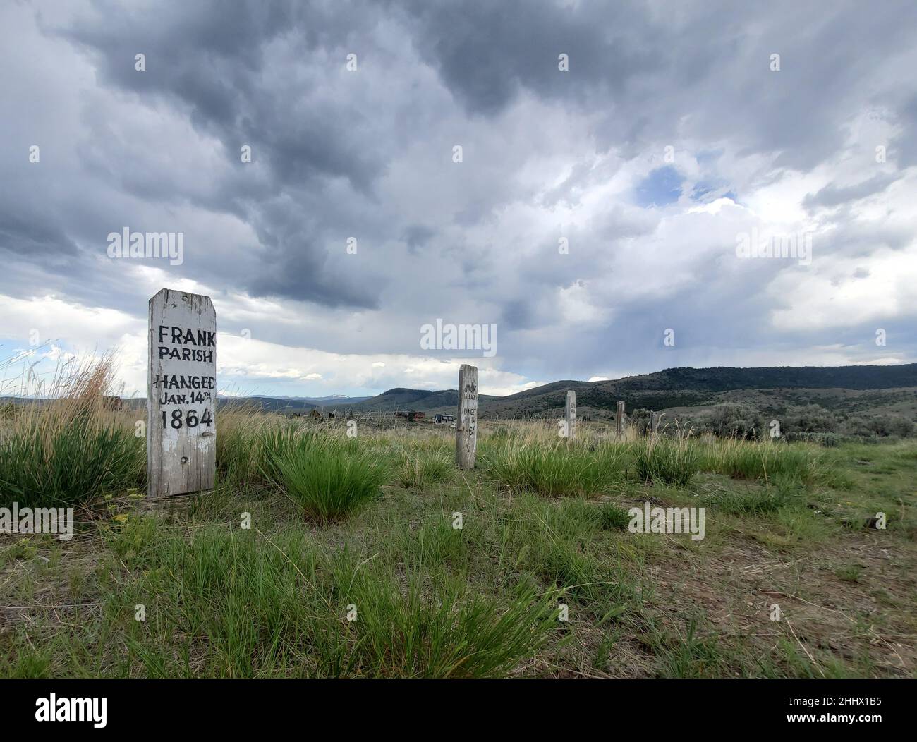 Hölzerner Grabstein für Frank Parish auf dem Boot Hill in Virginia City, Montana, mit dramatischen Wolken darüber. Stockfoto