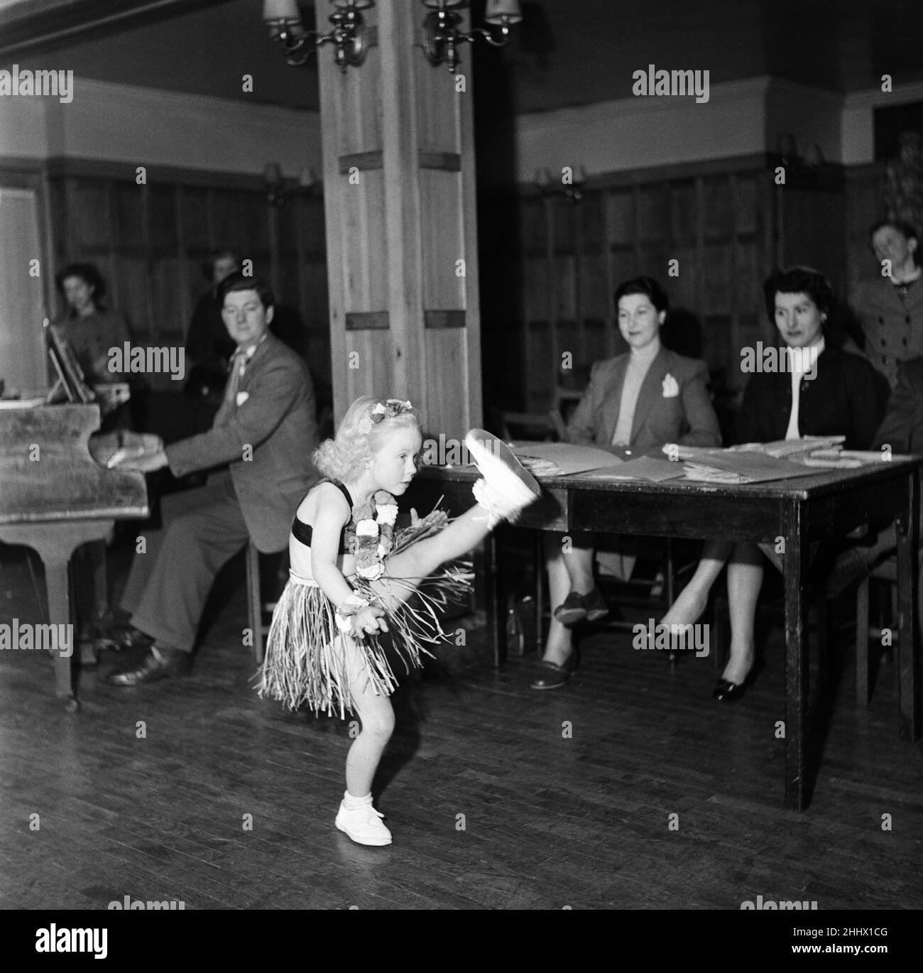 Im Arts Theatre, gleich neben dem Leicester Square, brachten Mütter ihre talentierten Kinder mit, um für einen neuen Harold Baim-Produktionsfilm mit dem Titel „Starting Young“ vorgesprochen zu werden. Die Kinder waren zwischen 5 und 15 Jahre alt und ihre kurzen Skizzen variierten von Gesang und Tanz über Rezitationen bis hin zu akrobatischem Tanz. Die kleine Carol Dilworth (6) von Harrow durchläuft ihren hochkickenden Tanz in ihrem Hula Hula Rig-out vor den Richtern beim Vorsprechen. 11th. April 1954. Stockfoto