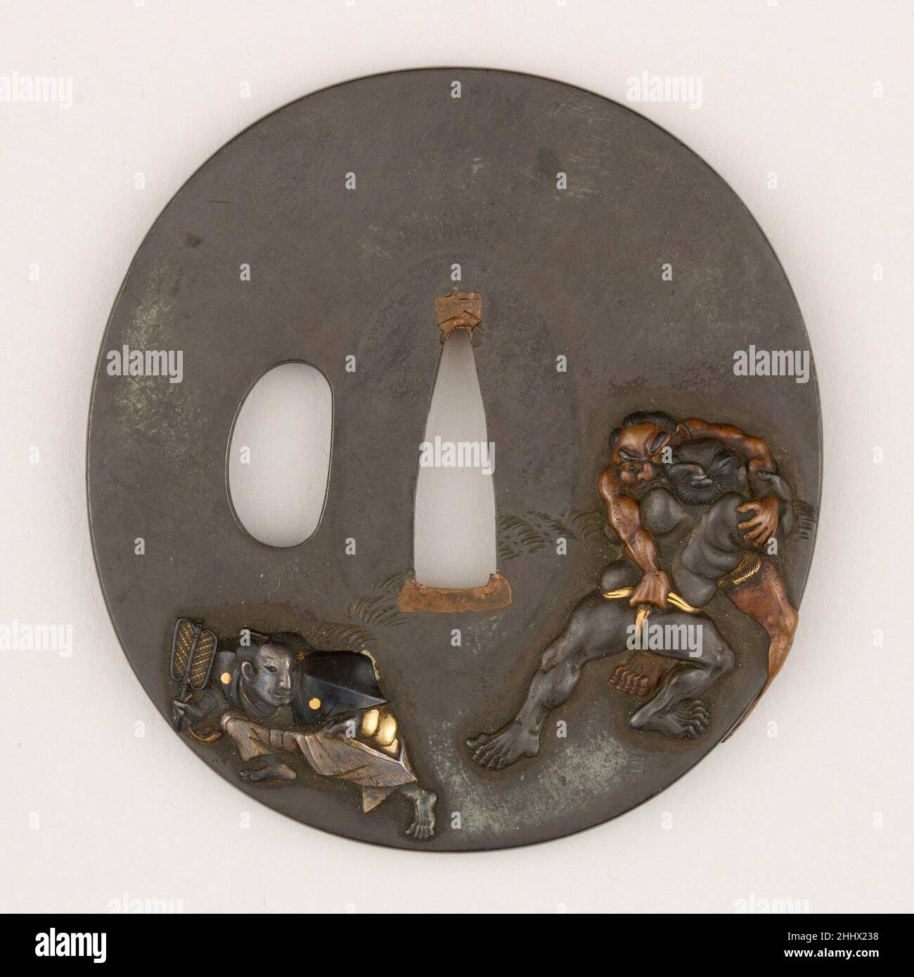 Schwertwächter (Tsuba) mit Sumō Wrestling-Motiv (相撲図鐔) ca. 1615–1868 Japanisch Diese polierte Shibuichi-Tsuba zeigt auf ihrer Vorderseite zwei Sumō-Ringer und einen Schiedsrichter. Die Rückseite ist neben dem Strohhalm des Ringes und dem Eimer mit „Power Water“ (chikara-mizu, 力水), aus dem ein Ringer vor einem Kampf feierlich seinen Mund ausspült, undekoriert. Schwertwächter (Tsuba) mit Sumō Wrestling-Motiv (相撲図鐔) 25715 Stockfoto