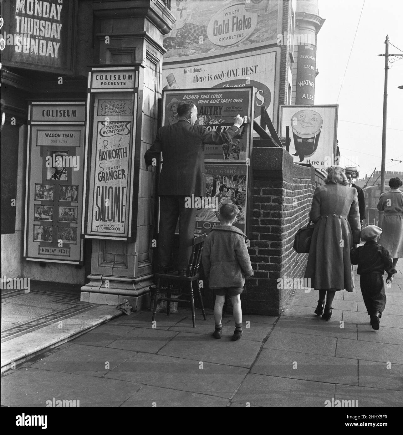 Der Manager des Coliseum Cinema, das sich auf der nordwestlichen Seite der Harrow Road neben dem Regent Canal im westlichen Londoner Stadtteil Paddington befindet, sah hier, wie er Poster aufstellte, um die neuesten Filme zu bewerben. 26th. März 1954 Stockfoto
