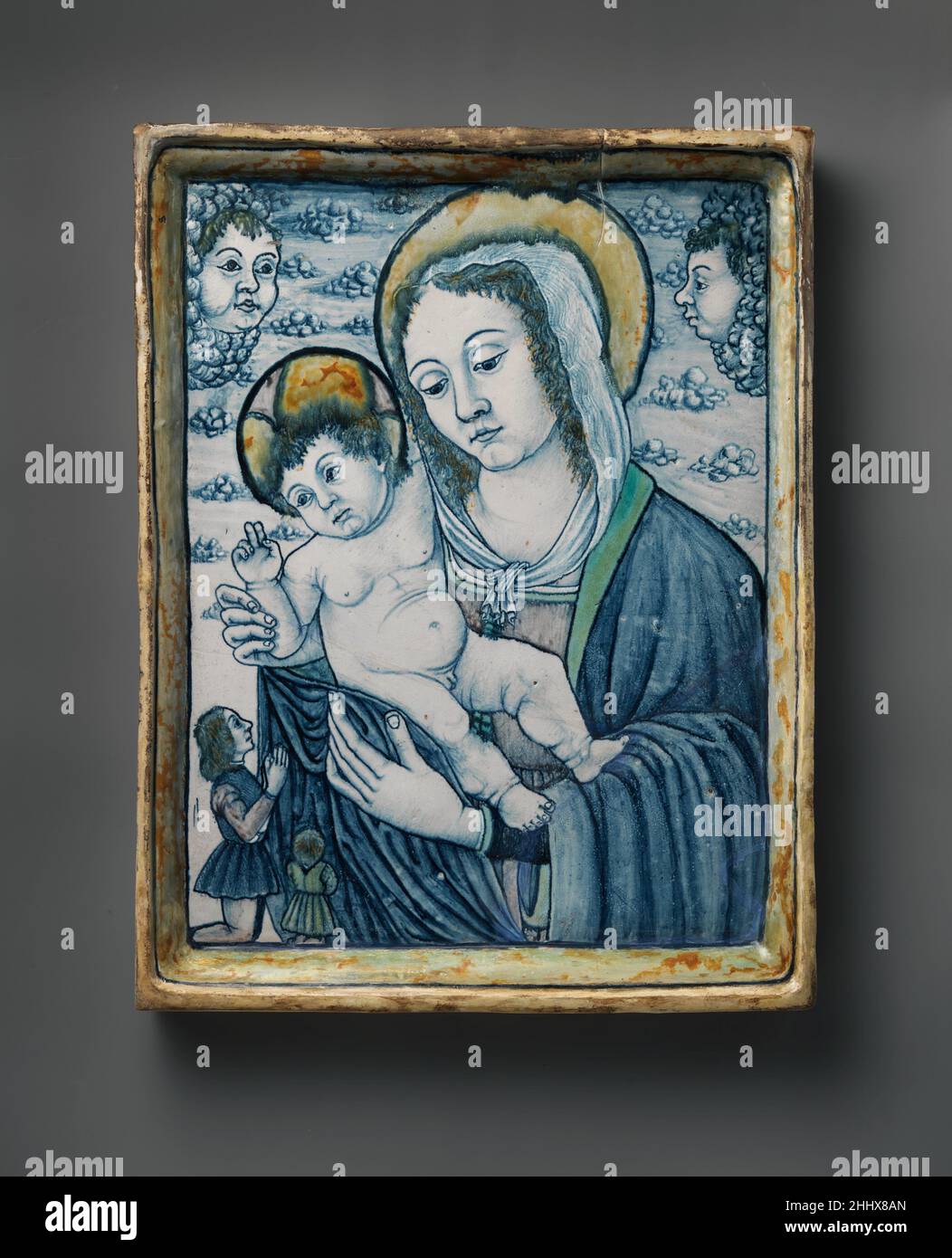 Andachtsschild mit der Madonna und dem Kind mit Stiftern ca. 1490–1500 Italienisch, vielleicht Emilia-Romagna (möglicherweise Faenza) oder die Marken im Gegensatz zu vielen maiolica-Objekten hat diese Tafel keine Funktion, außer dem Betrachter ein gemaltes Bild zu zeigen. Es behält das Gefühl der Domestizität mit Renaissance maiolica Gefäße und Geschirr verbunden, wurde aber gemacht, um religiöse Hingabe zu fördern. Das kleine Format und die eng zugeschnittene Ansicht der Jungfrau mit dem Kind schaffen eine intime Beziehung zum Betrachter, und die kleinen knienden Spender unten links stellen ein Modell für die Anbetung im Haus dar. Die Plaque Imita Stockfoto