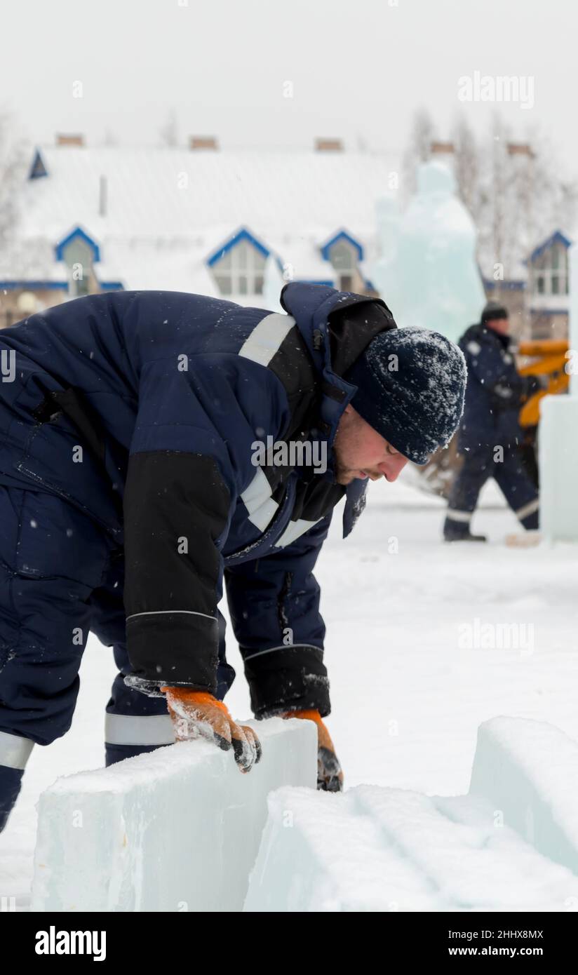 Mann lädt Eisplatten auf Holzschlitten Stockfoto