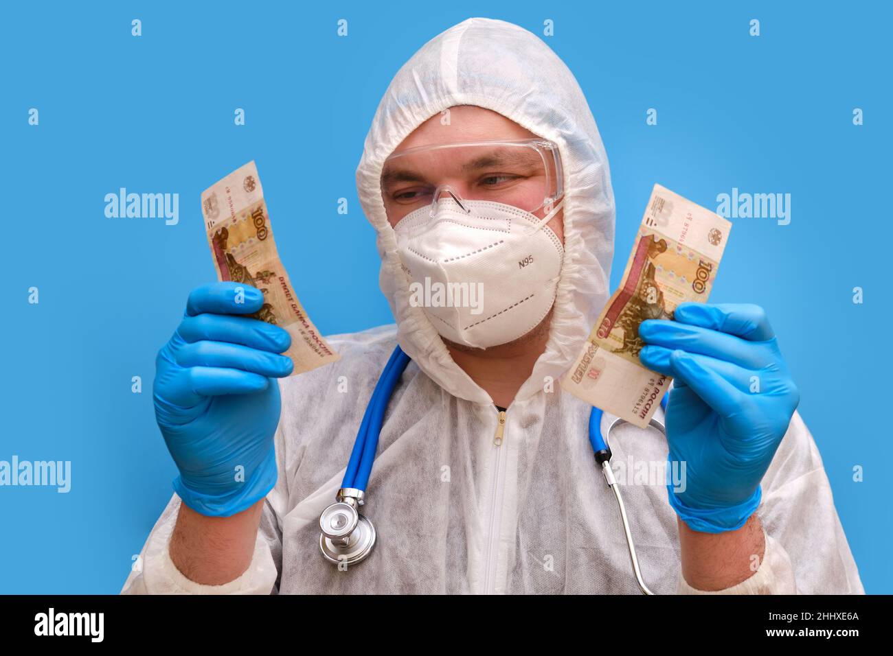 Mann Arzt Sanitäter in einem Schutzanzug Uniform mit Brille und Gesichtsmaske auf einem Studio blauen Hintergrund. Sanitäter in weißer antiviraler Schutzkleidung Stockfoto
