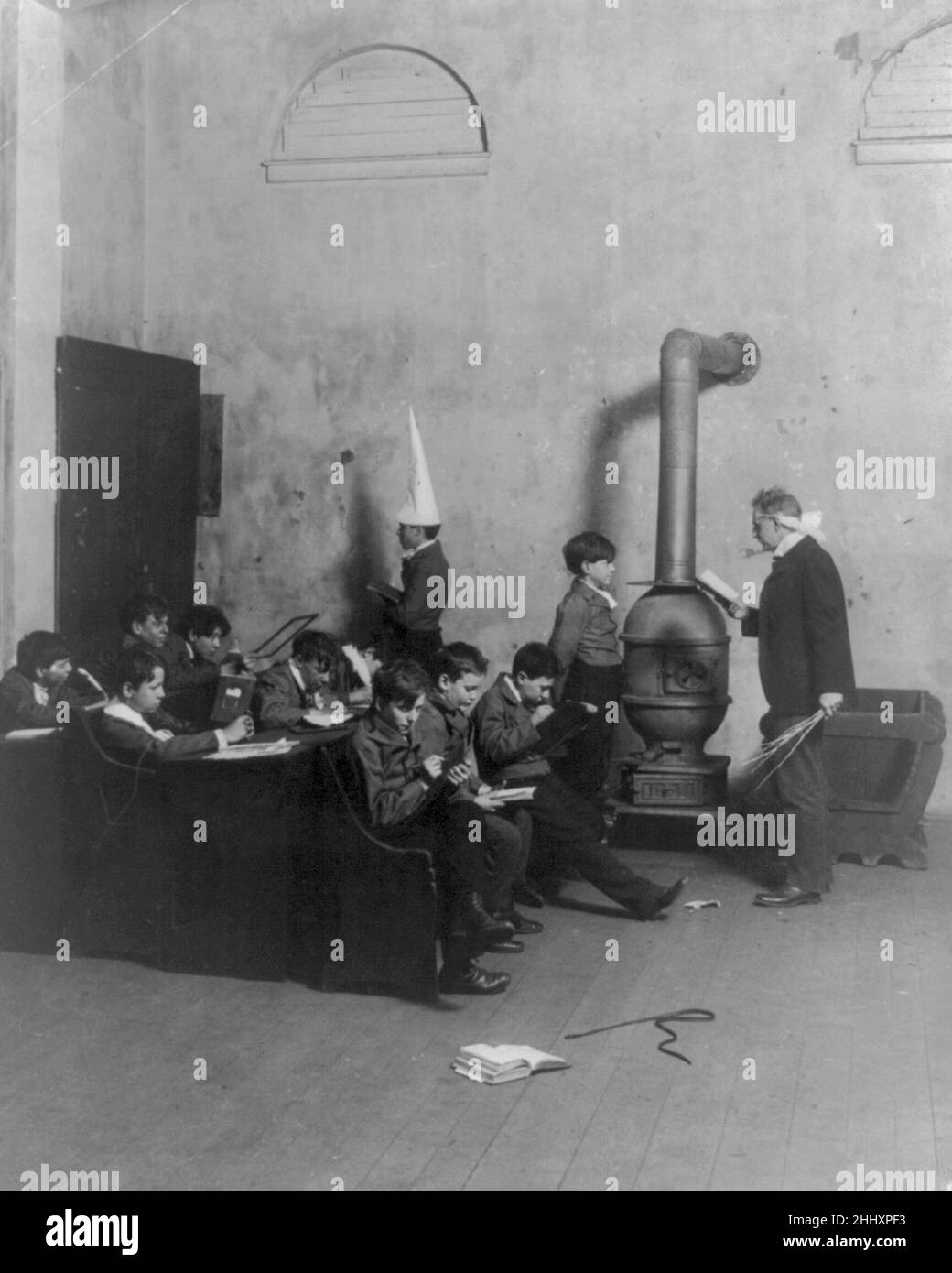 Eine Old Fashioned Boys School mit einem armen Jungen, der eine Dunce-Mütze tragen und in der Ecke stehen muss - 1905 Stockfoto